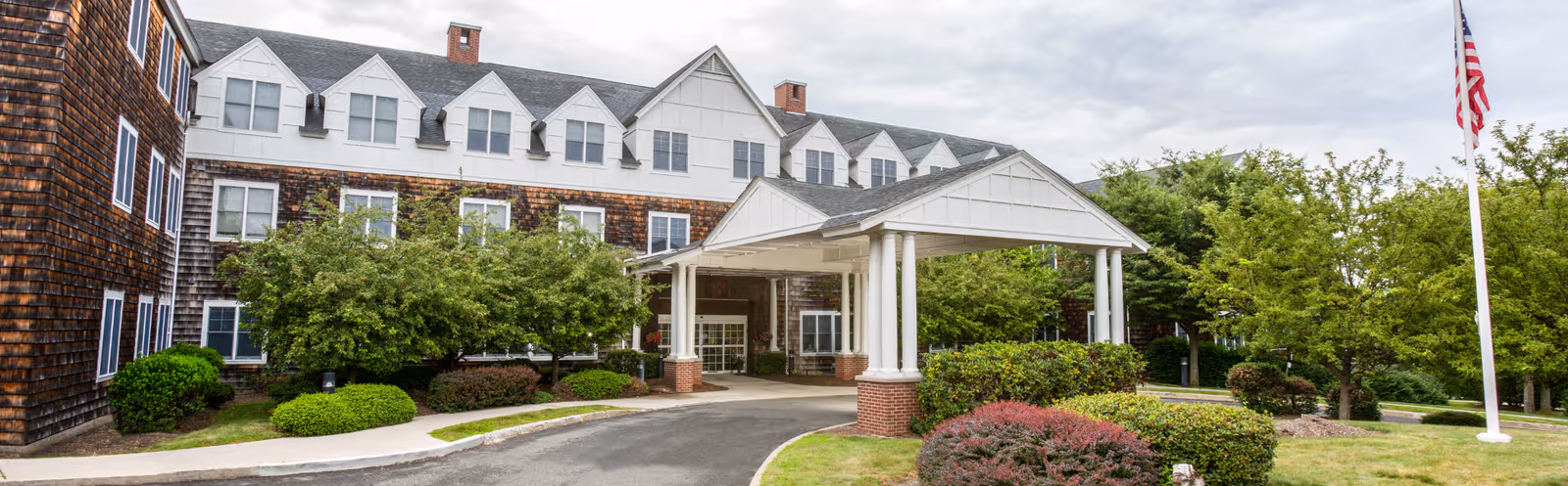 Exterior view of Benchmark Senior Living at Hamden with entrance portico and landscaping.
