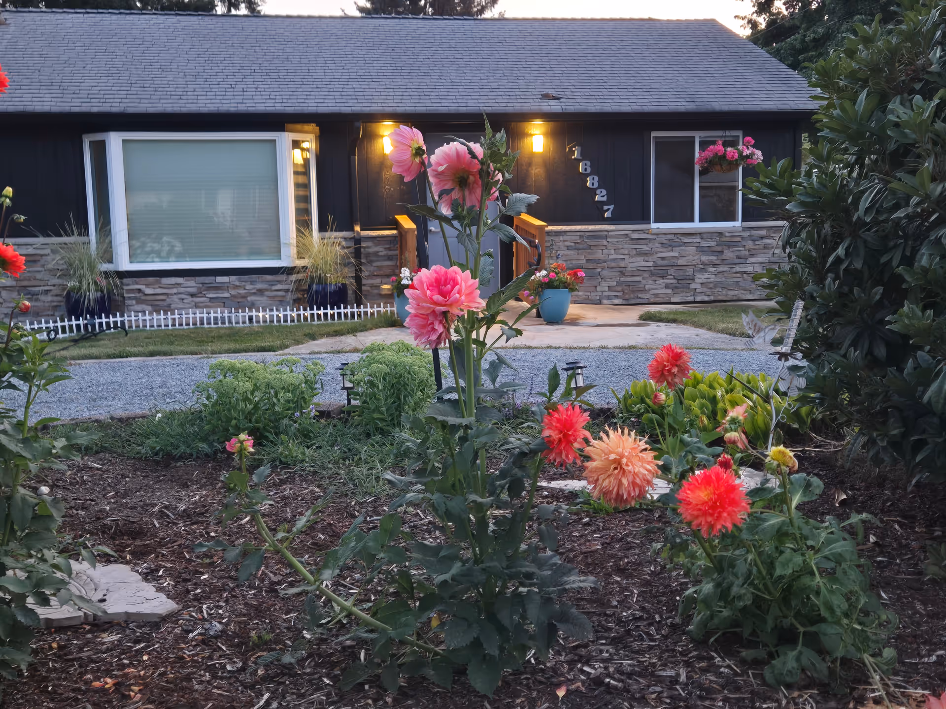A single-story facility with stone facade and a colorful garden in the foreground.