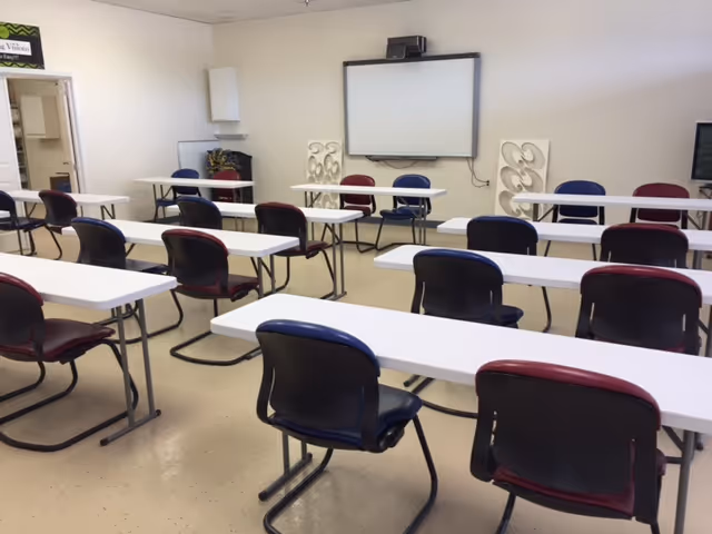 Interior classroom-style room in a senior facility with desks and a projector