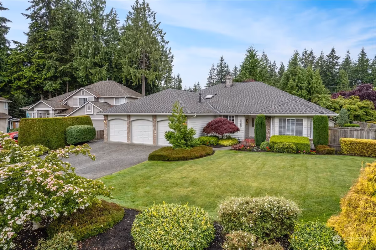 Front view of a single-story home with manicured lawn and surrounding shrubbery.