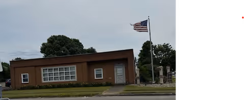 Exterior view of a brick senior care facility with flagpole and landscaped yard.