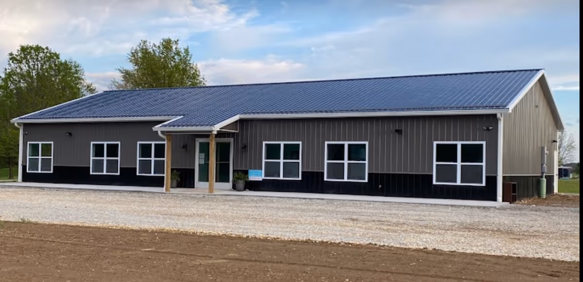 Exterior view of a single story building with a blue metal roof and front entrance.