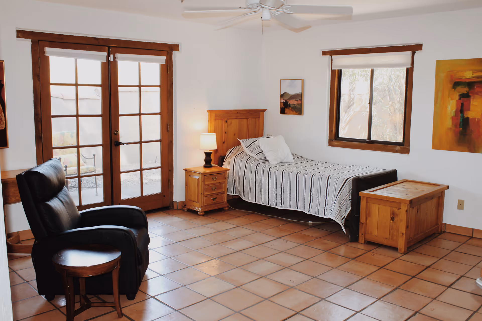 Cozy bedroom featuring a single bed, recliner, nightstand, and French doors.