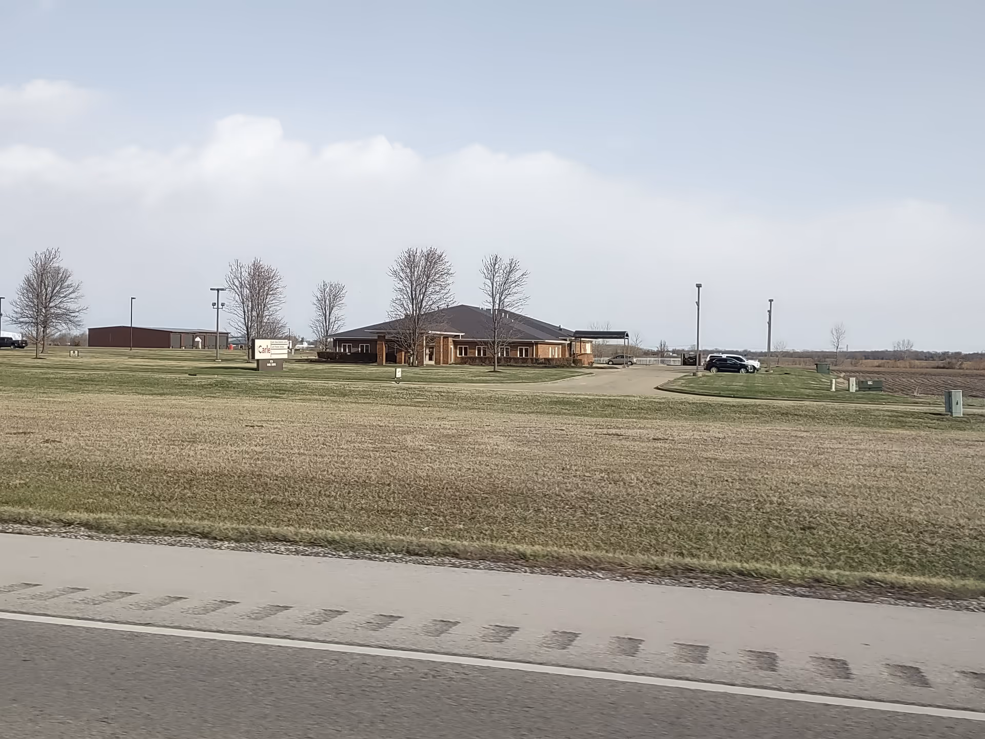 Front view of a Dynamic Homecare Inc facility: brick building with a dark roof and lawn.