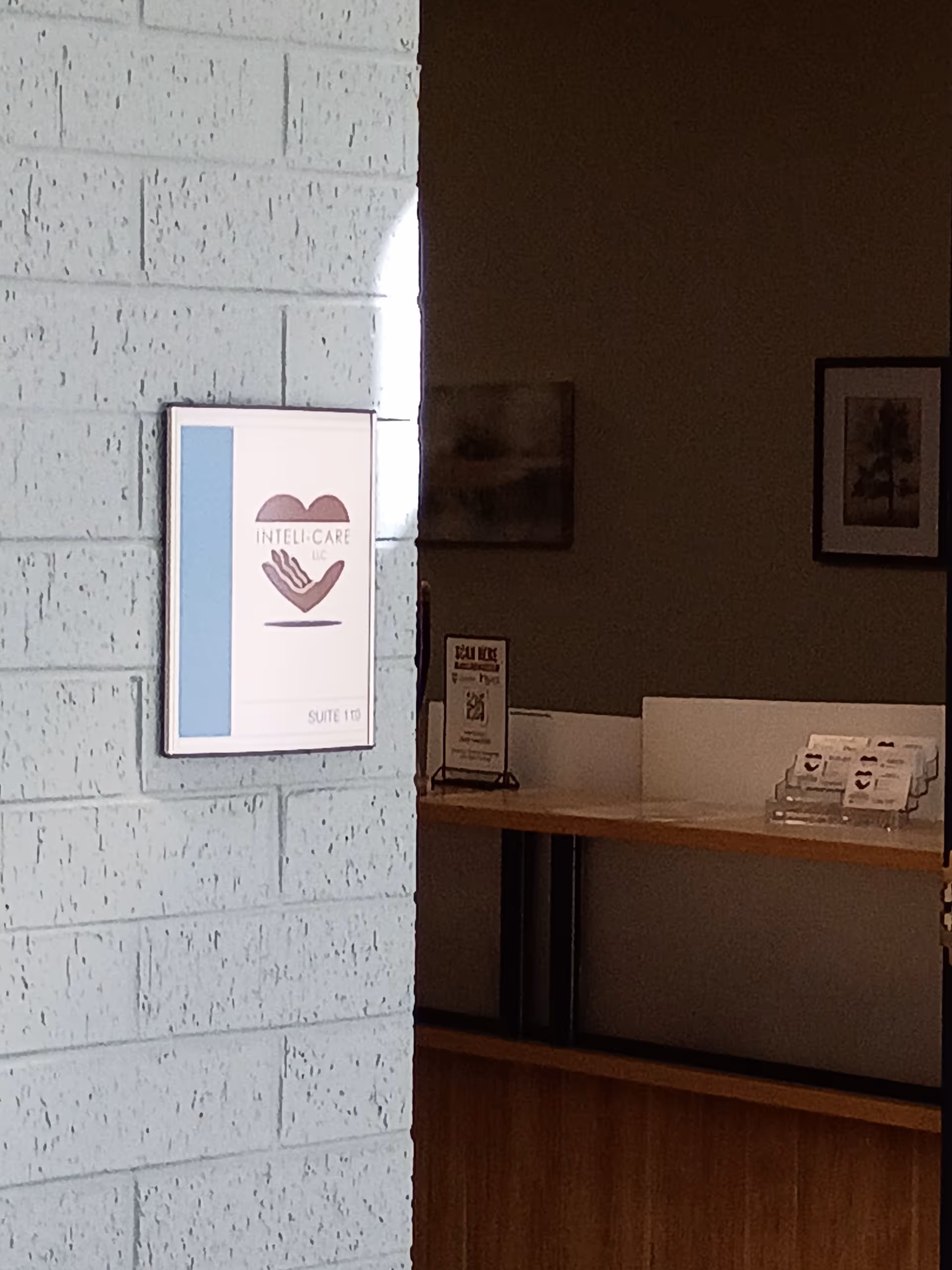 Interior hallway with Inteli-Care LLC sign on light blue brick wall near a reception desk
