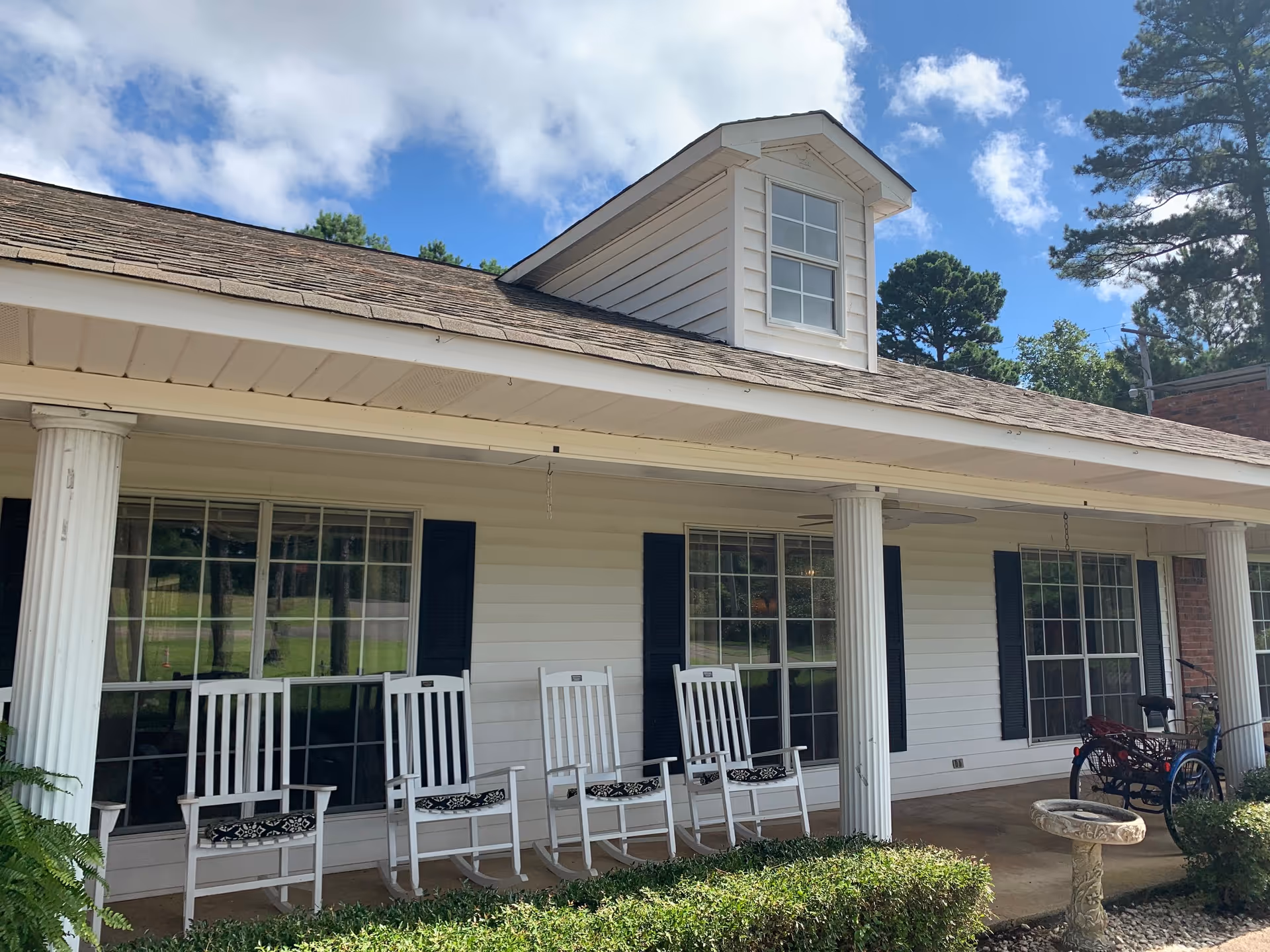 Front porch of Pinecrest Retirement Lodge with white rocking chairs.