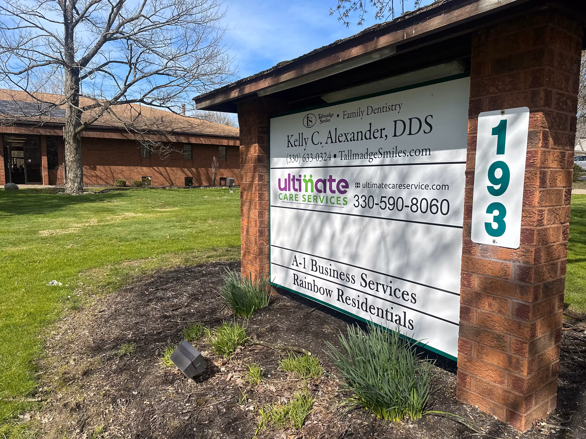 Brick entry sign for Ultimate Care Services beside a grassy lawn