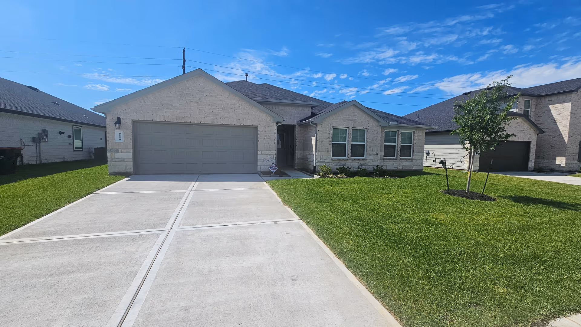 Front view of a single-story house with a wide driveway and green lawn.