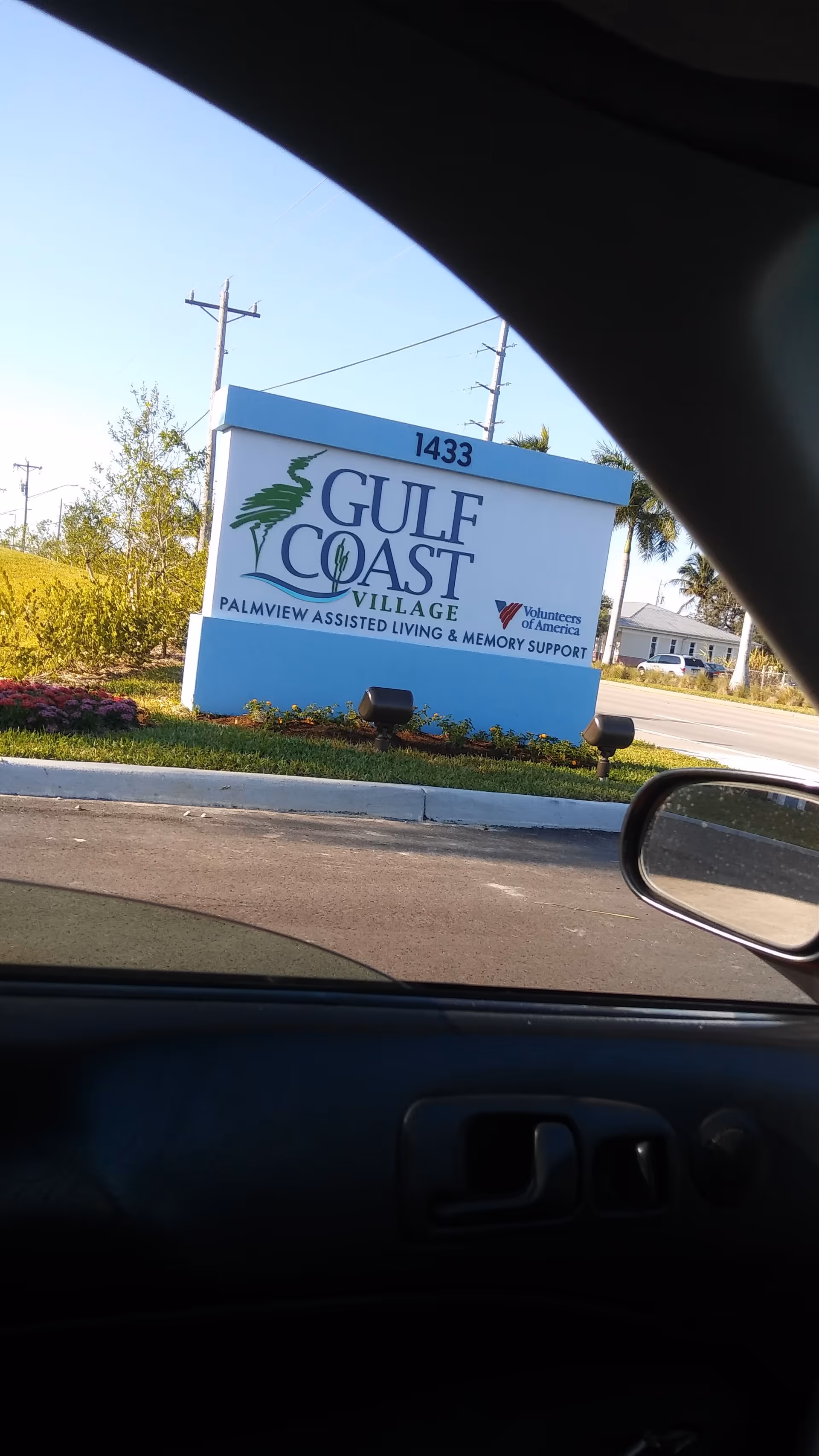 Exterior view of Gulf Coast Village sign at the facility entrance on a sunny day