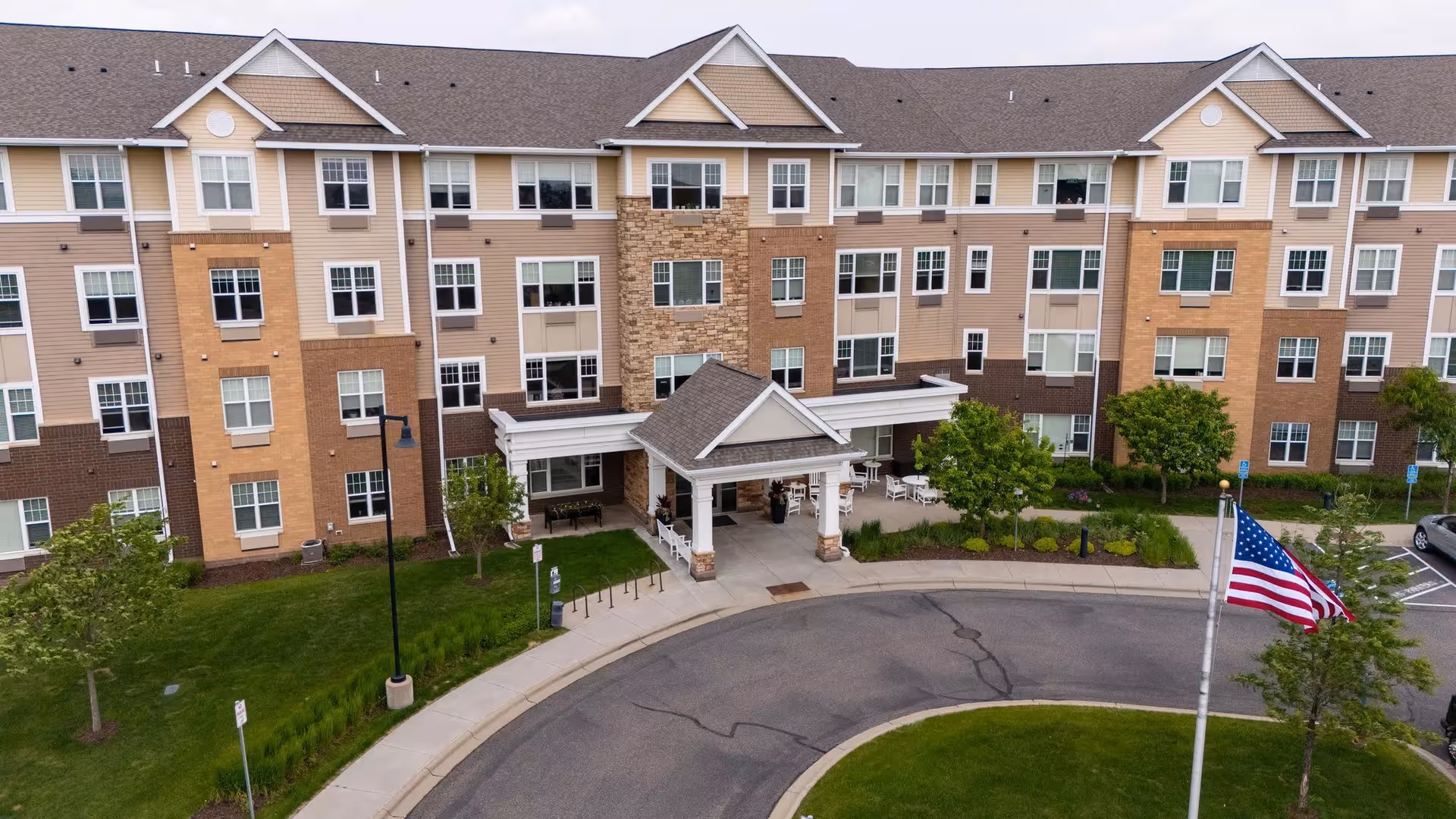 Exterior view of New Perspective Senior Living Oakdale with entrance, driveway, and American flag.