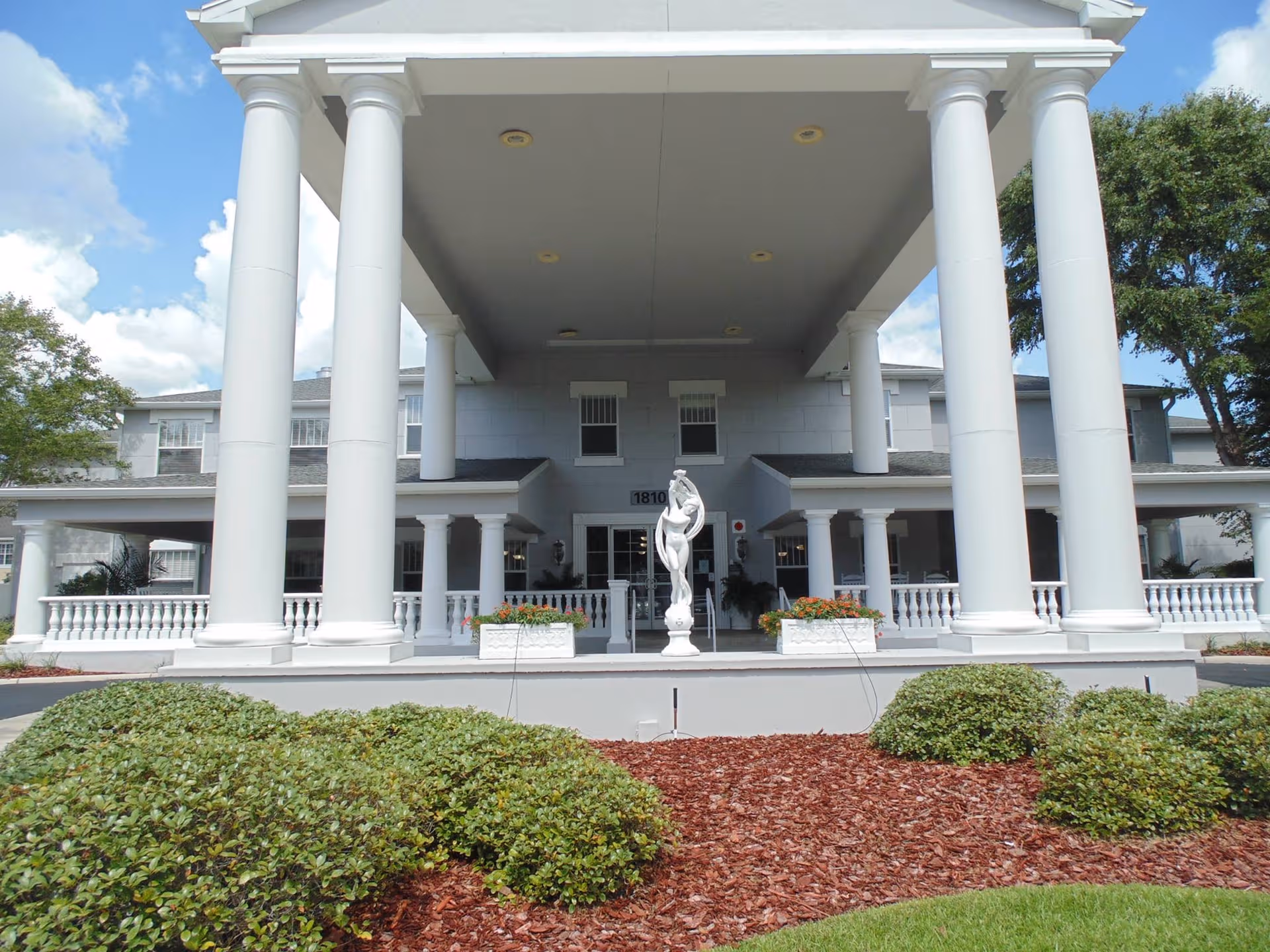 Front entrance of Hampton Manor Deerwood with large columns and statue.