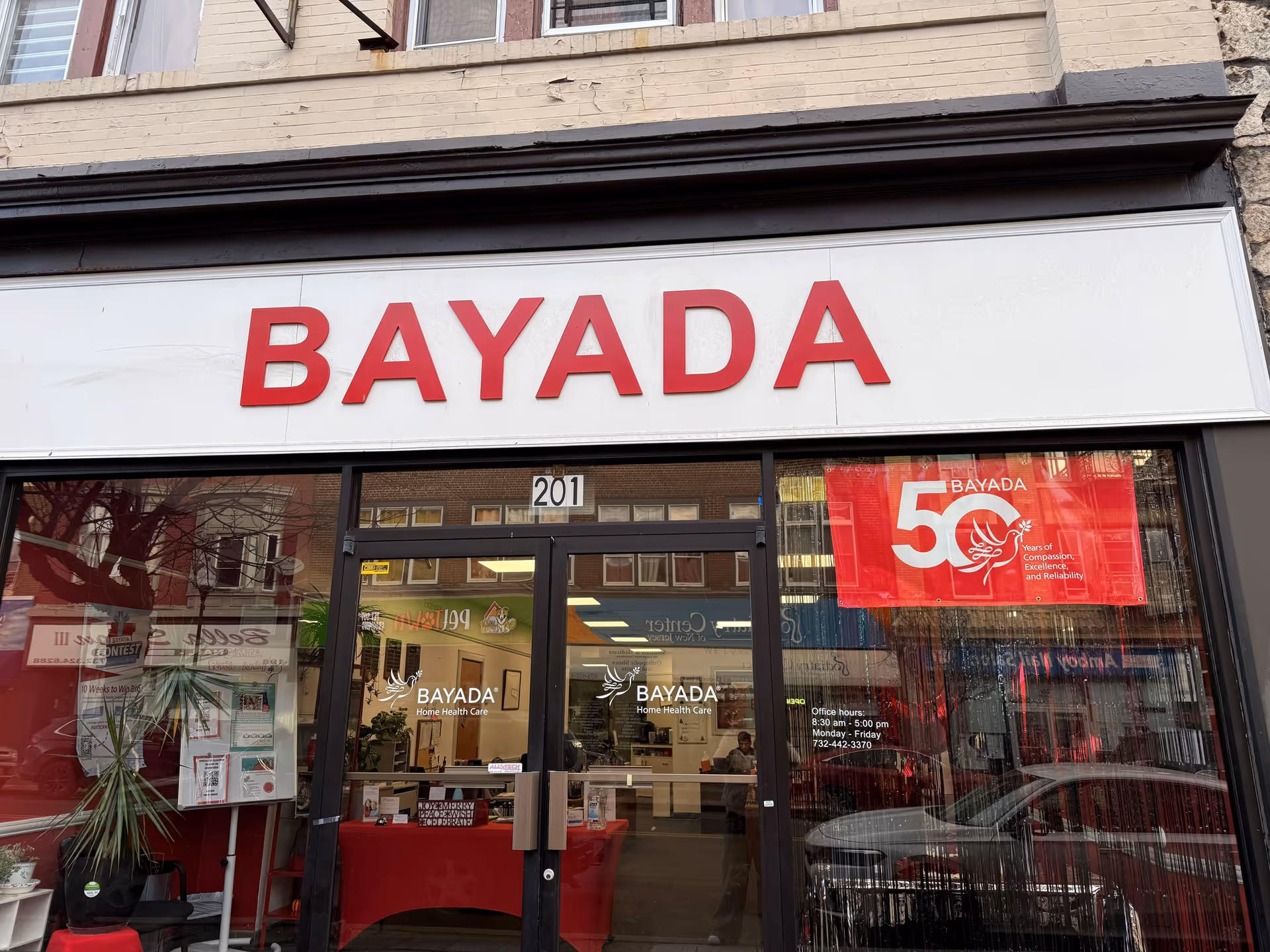 Storefront of BAYADA Assistive Care with large red BAYADA sign above glass doors.