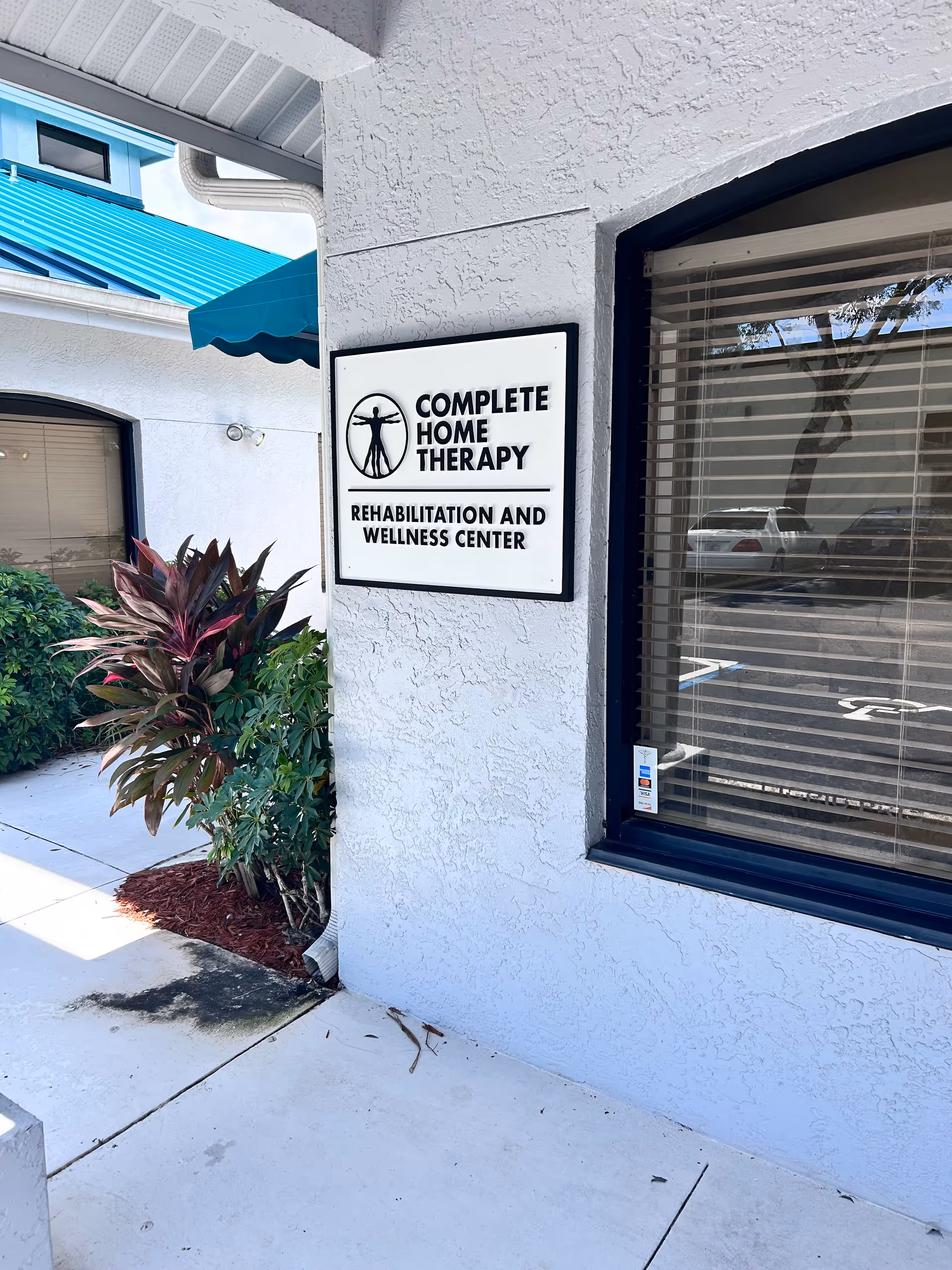 Exterior view of a building entrance with a Complete Home Therapy sign and blue awning.