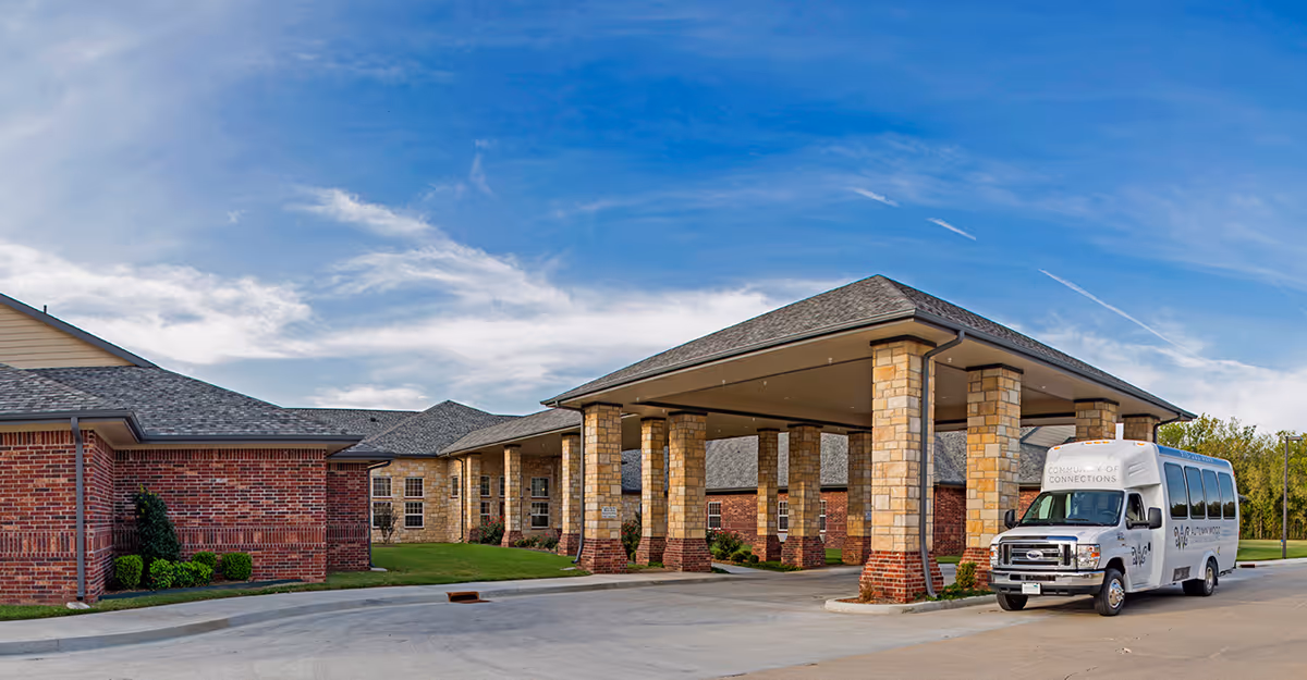 Exterior view of Emerald Care Center Claremore with a covered entrance and a shuttle bus.