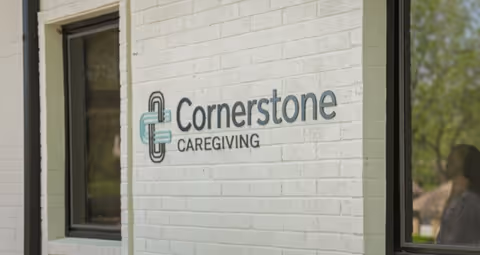 Exterior view of a white brick wall with the Cornerstone Caregiving sign.