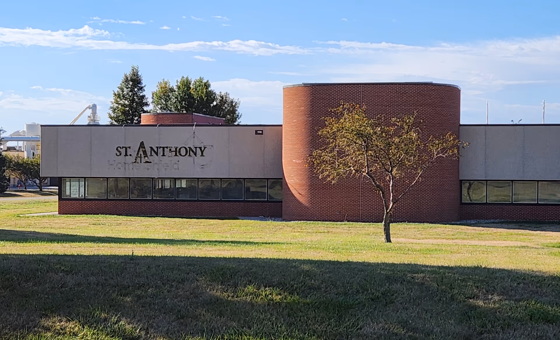 Exterior view of St. Anthony building with brick curved facade and tree on lawn