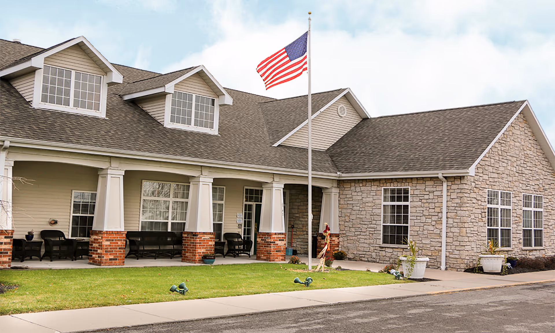 Front exterior of a Brookdale Niagara senior living facility with a flag and seating.