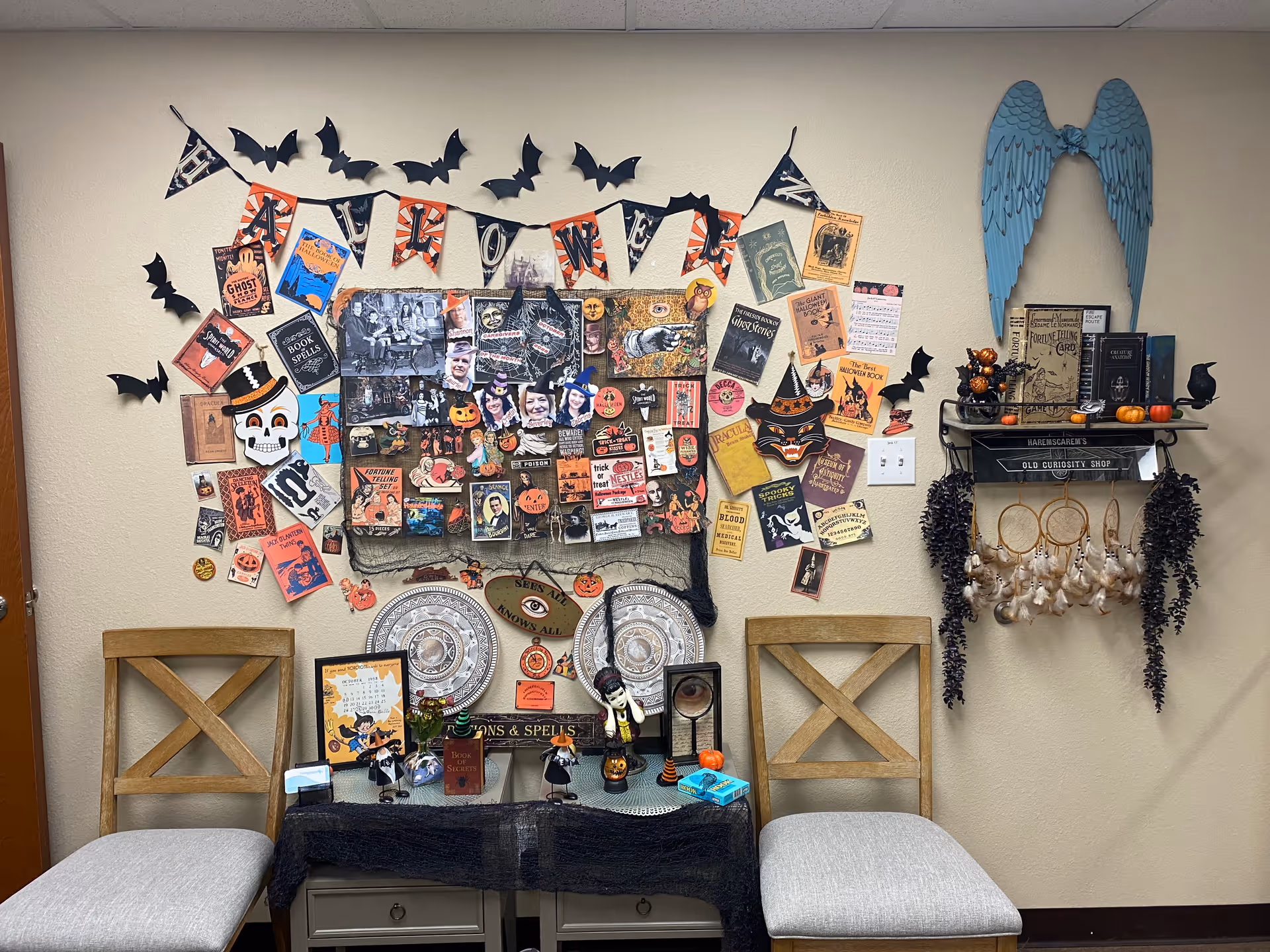 Interior wall display featuring Halloween decor, flyers, and two wooden chairs.