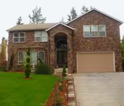 Front exterior view of a two-story brick care home with a driveway and garage.