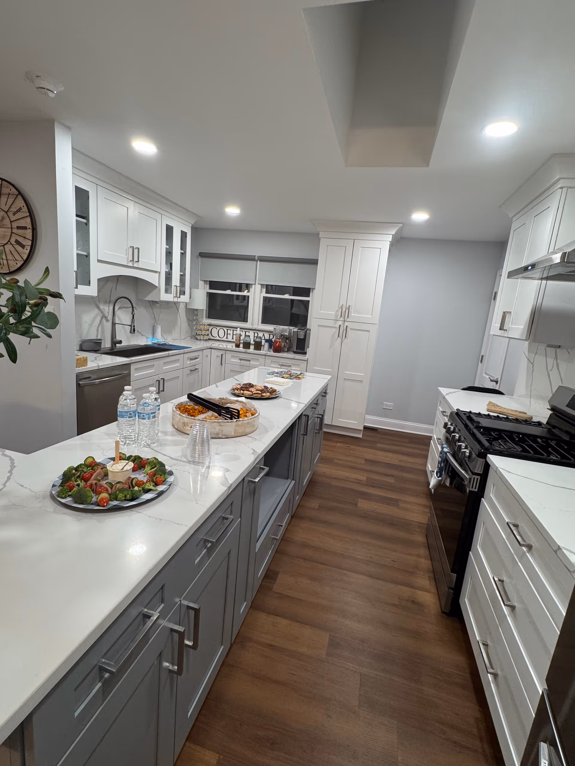Bright kitchen in a senior living facility with white cabinets, island, and food platters.