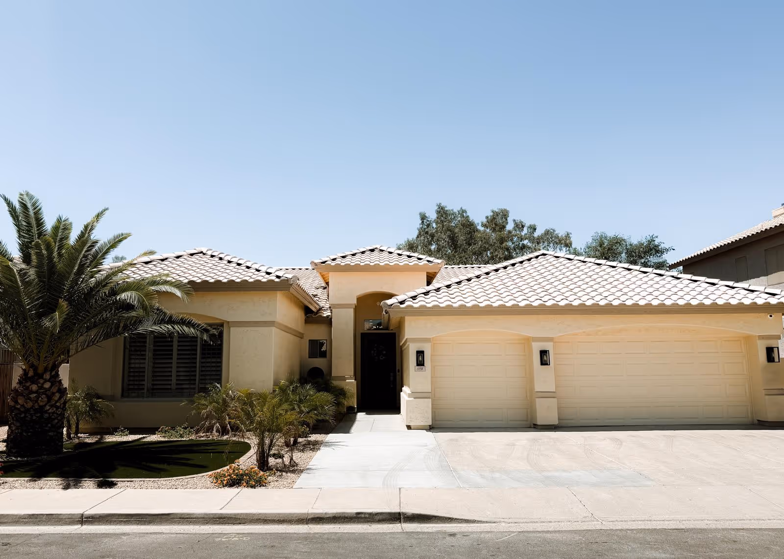 Front exterior view of a beige, tiled-roof senior living facility with driveway.