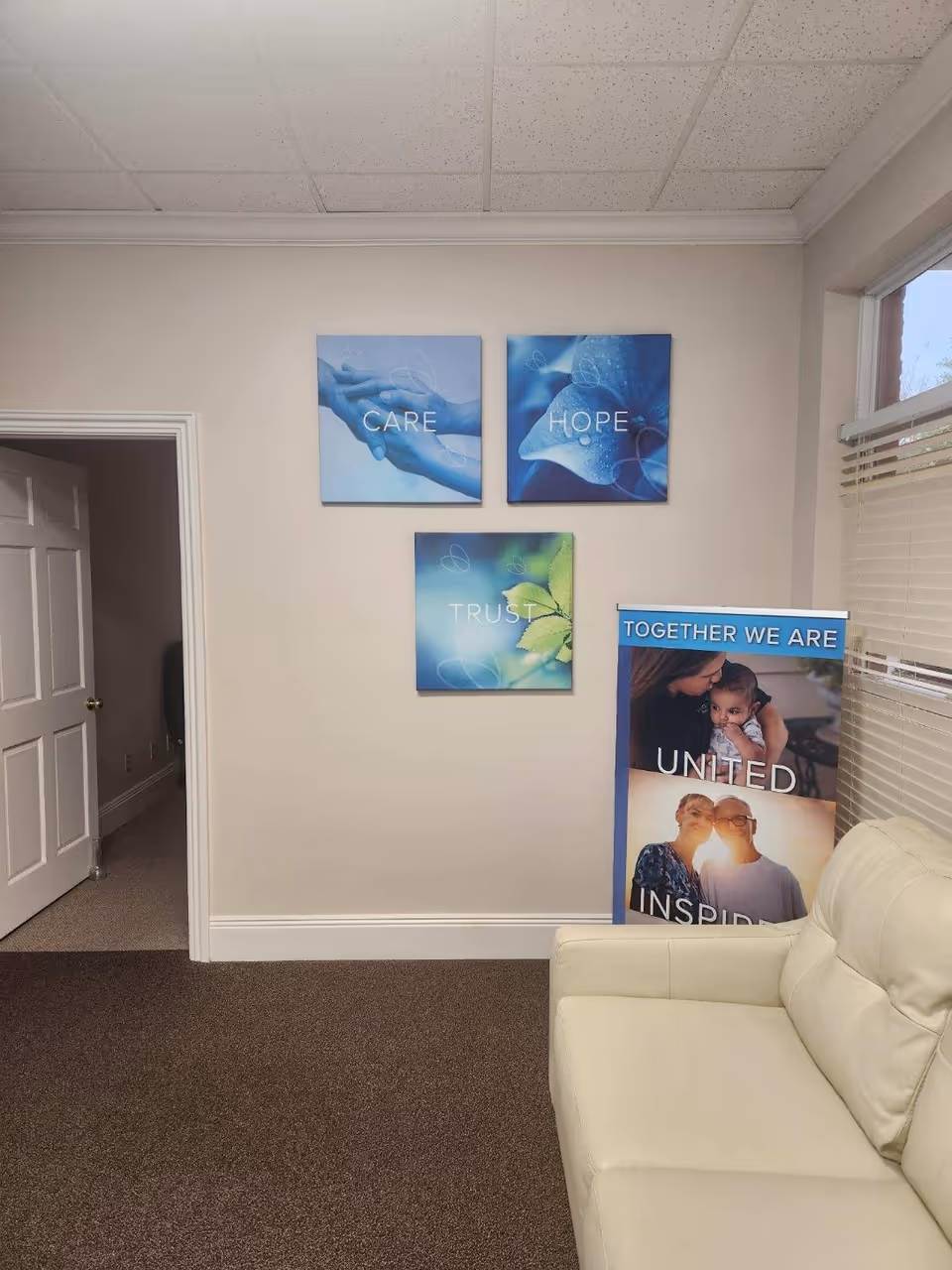 Interior lounge area in a senior care facility with a white sofa and wall art.