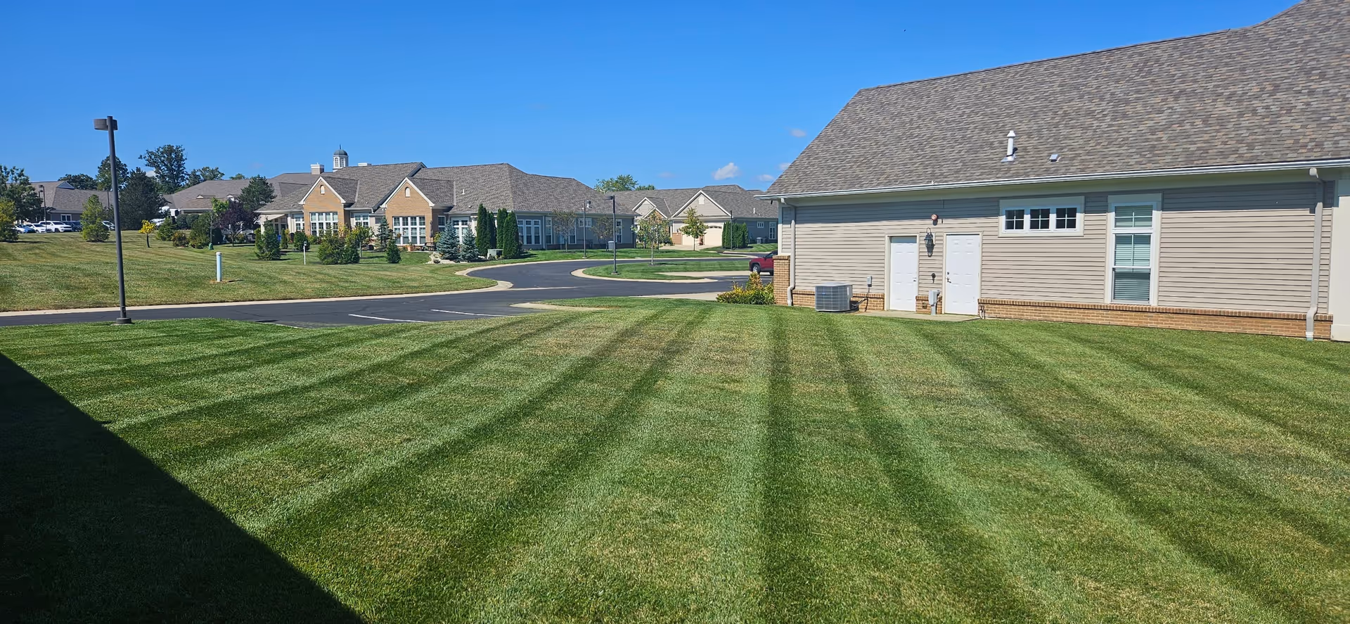 Wide exterior view of Knolls of Oxford campus with manicured lawn and beige building.
