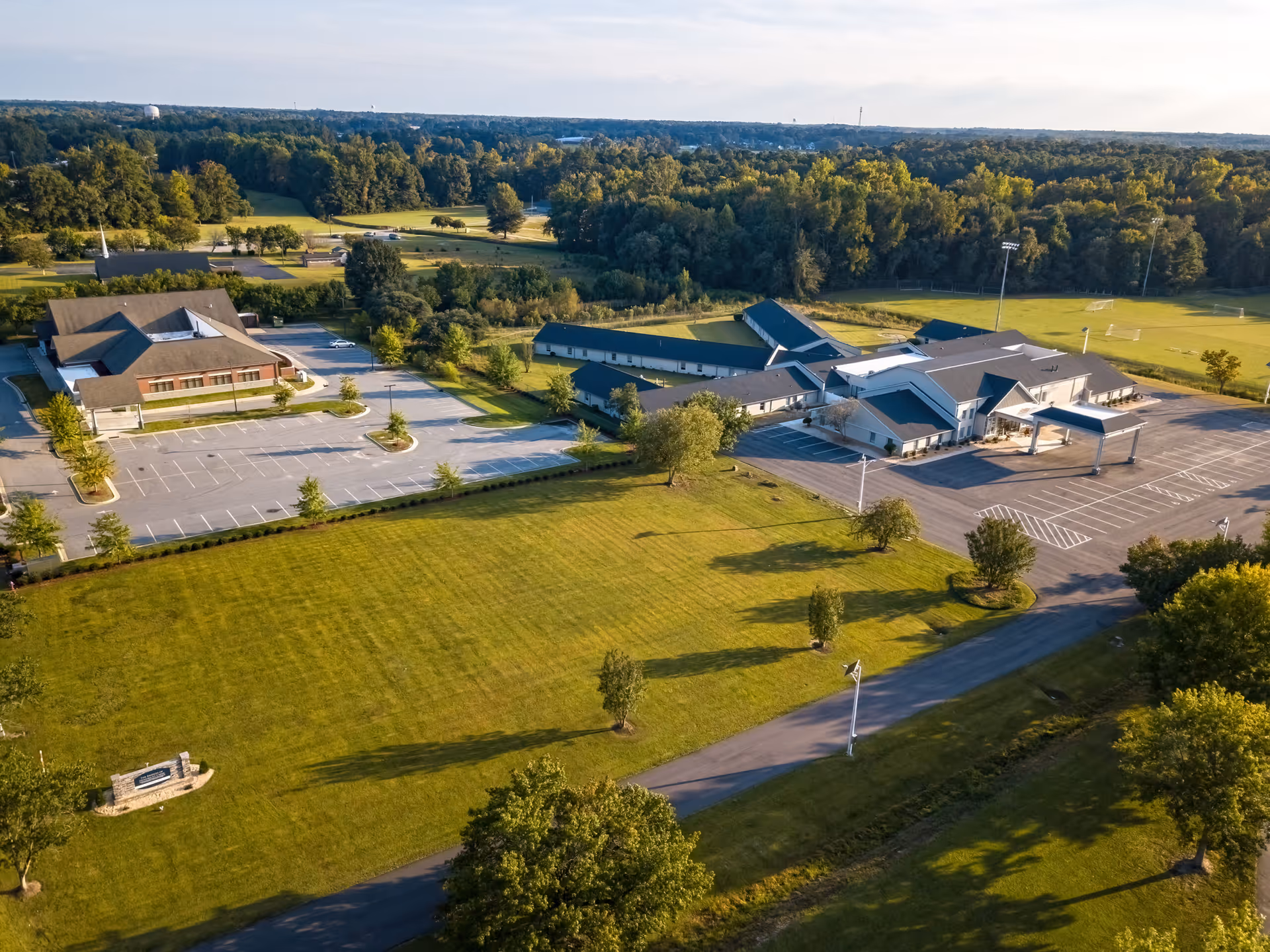 Aerial view of Open Fields Assisted Living campus with multiple buildings, parking, and green lawns.