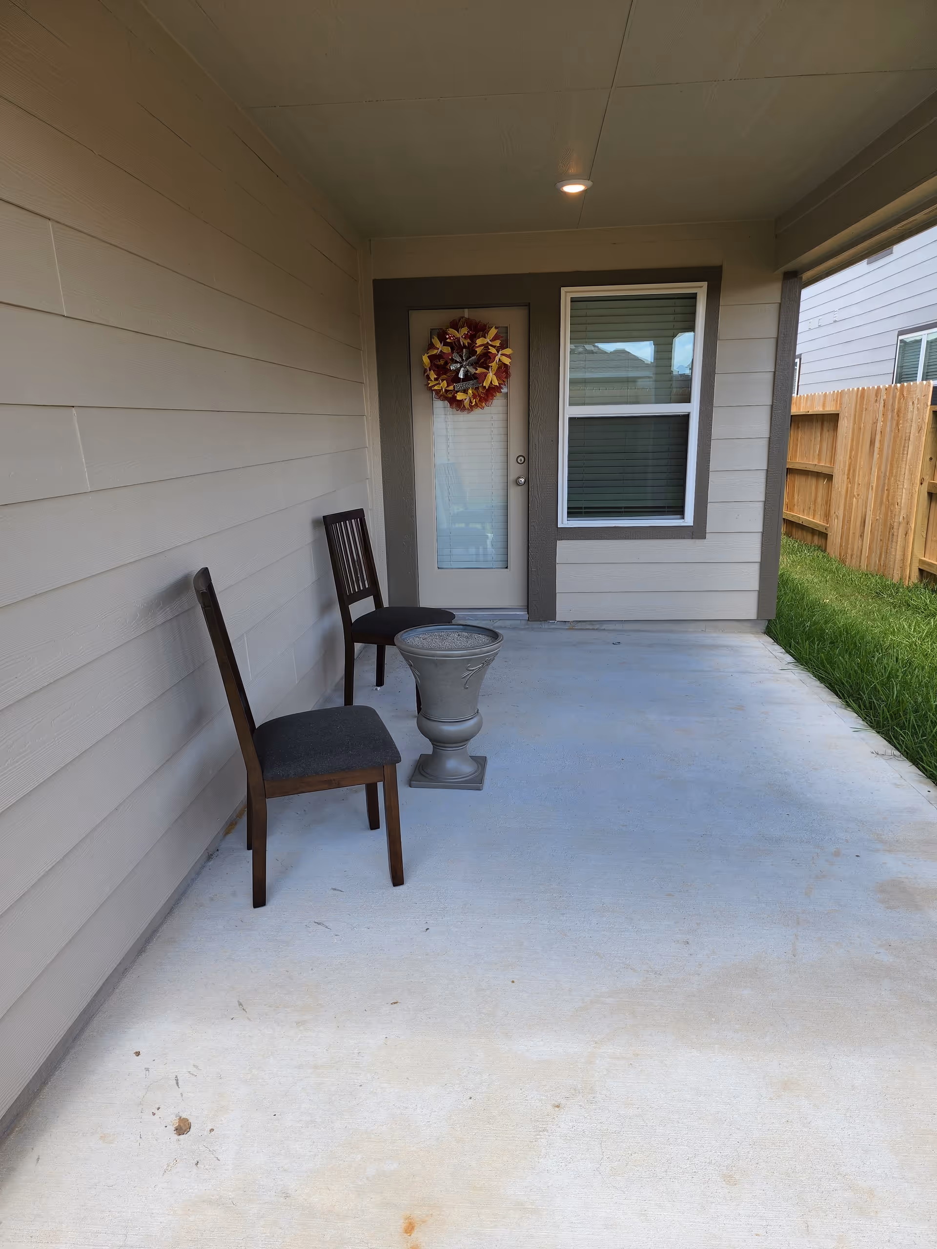 Front porch of a home with two chairs, a small table, and a wreath.