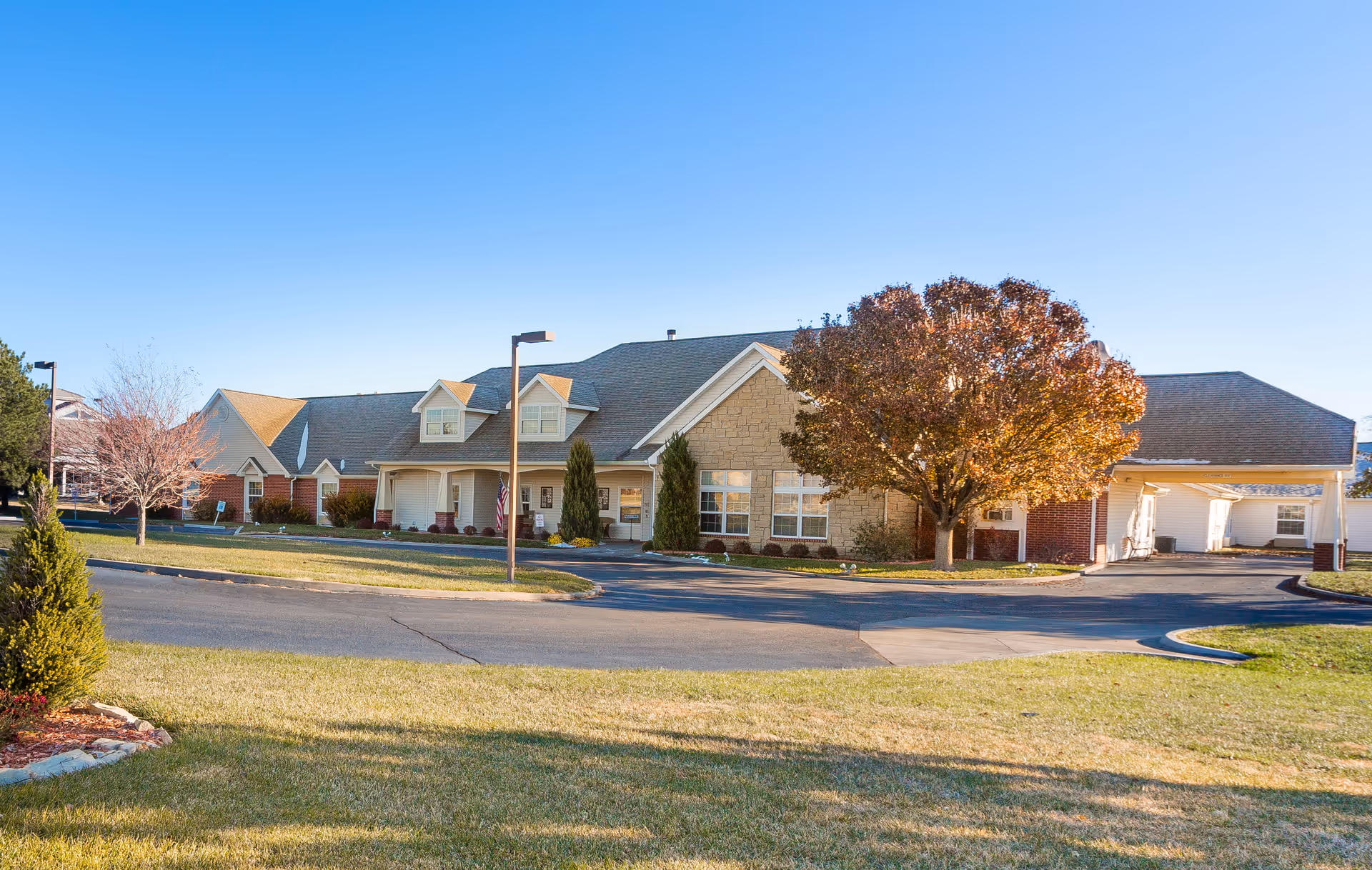 Exterior view of Brookdale Dodge City facility with driveway, lawn, and trees.