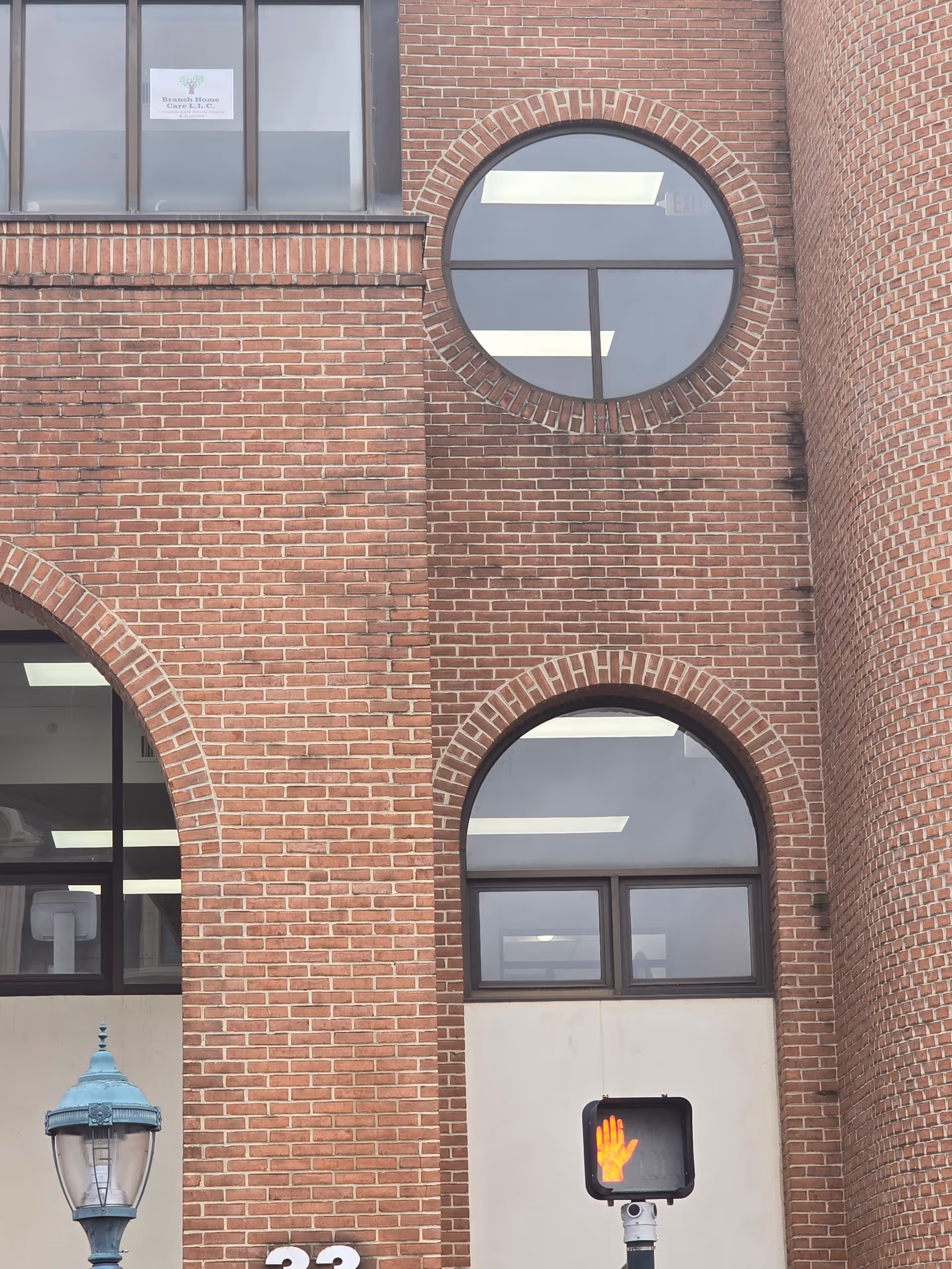 Brick building exterior with round arched windows and a small sign reading Branch Homecare LLC.