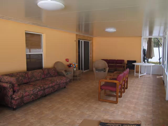 Covered outdoor patio with couches, chairs, tables, and ceiling lights along peach walls.