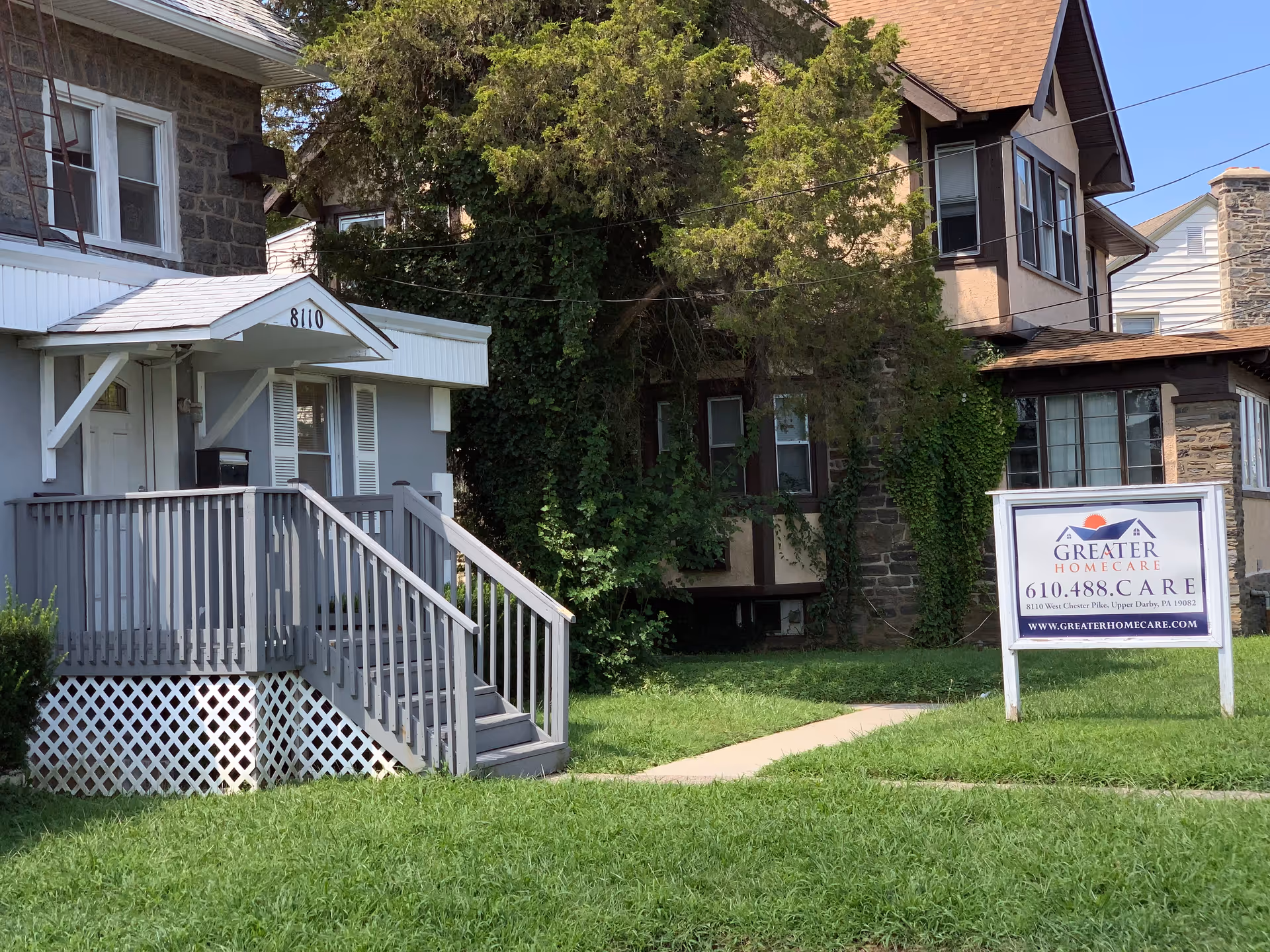 Exterior view of a facility with a porch, stairs, and a sign reading Greater Homecare.