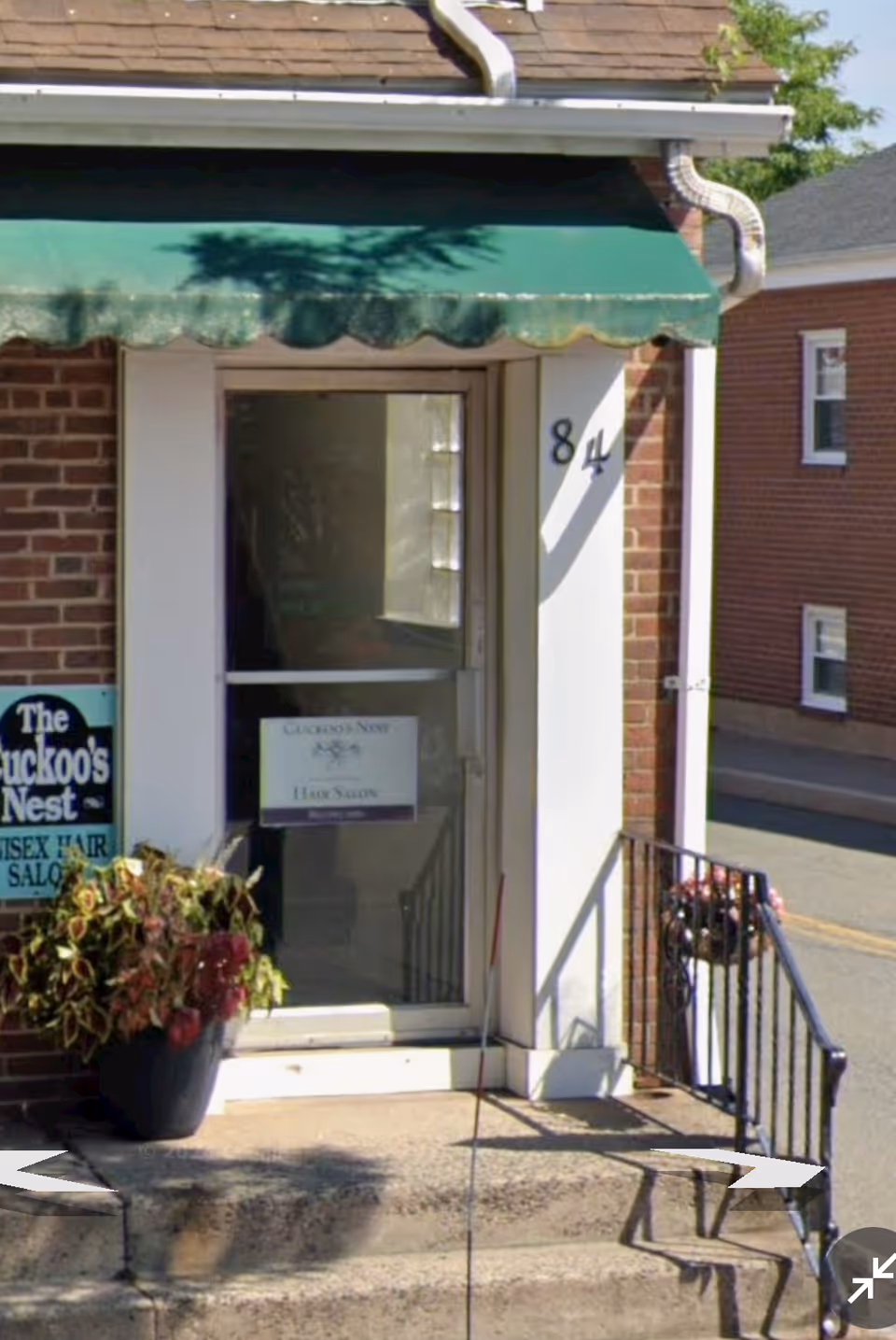 Brick building entrance with glass door and a green awning.