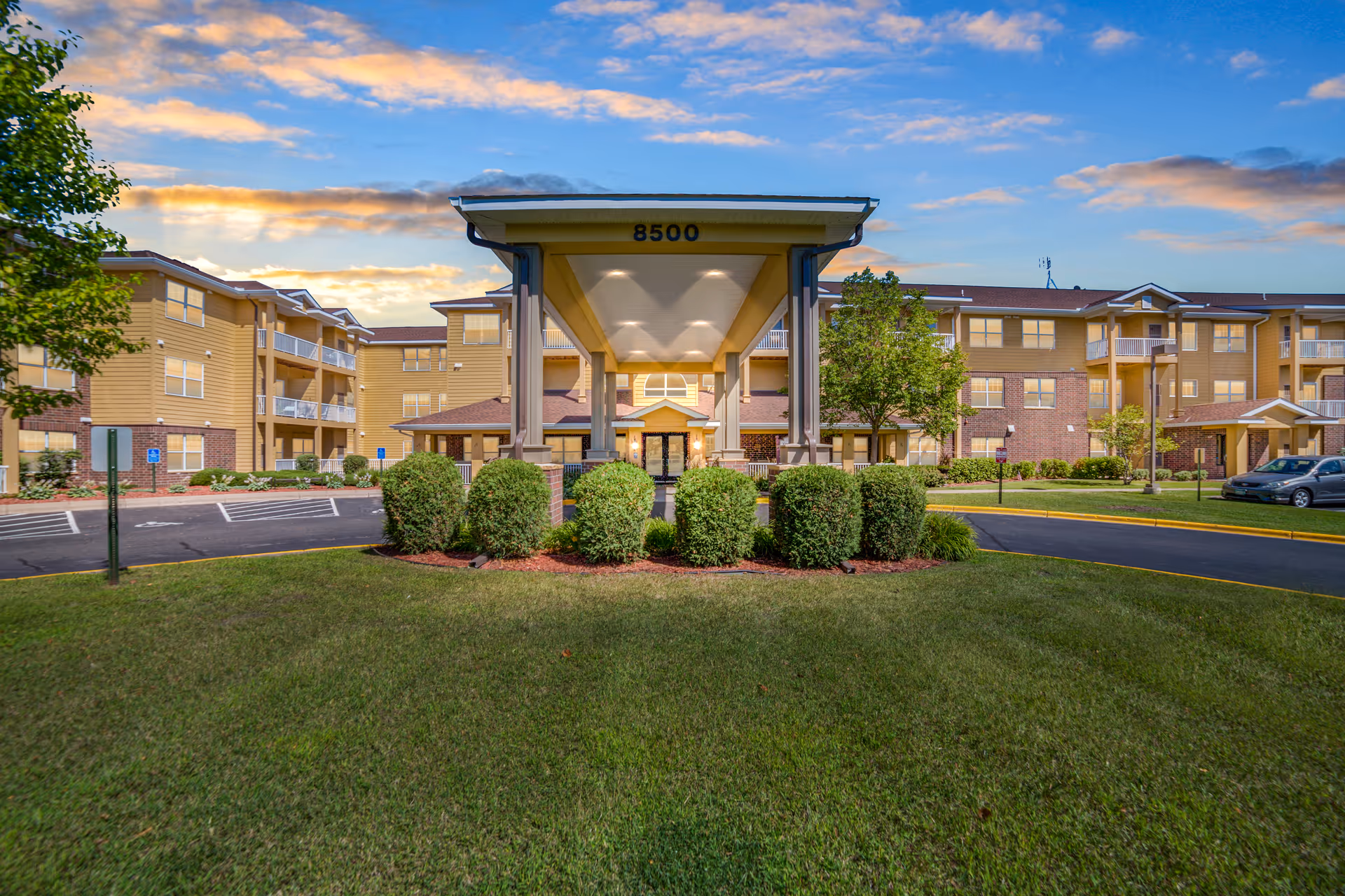 Exterior view of a senior living facility with a covered entrance and landscaped grounds.