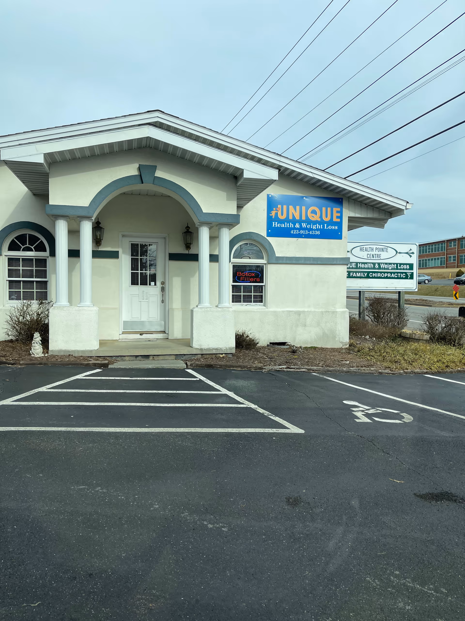 Exterior of a clinic with curved entrance and a sign reading Unique Health & Weight Loss.