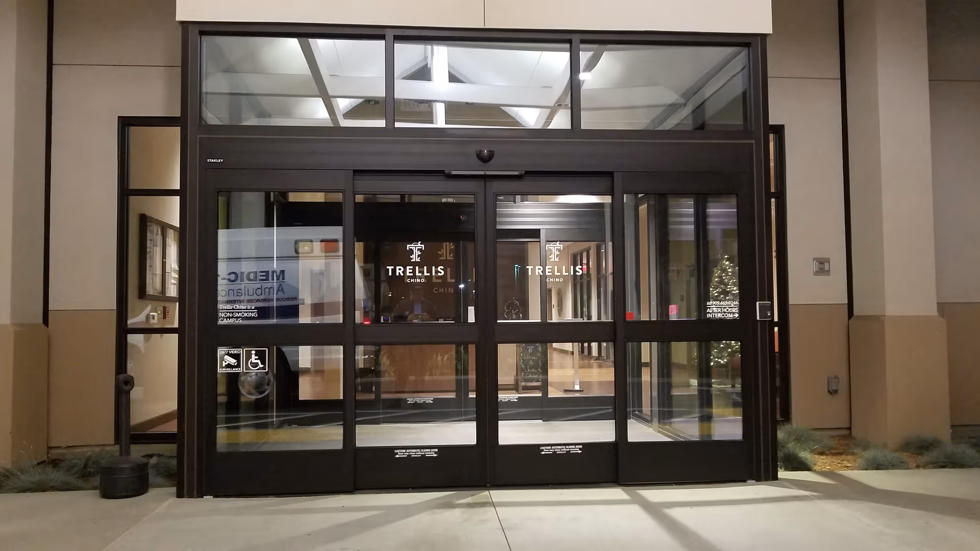 Glass front entrance of Trellis Chino facility with metal doors.