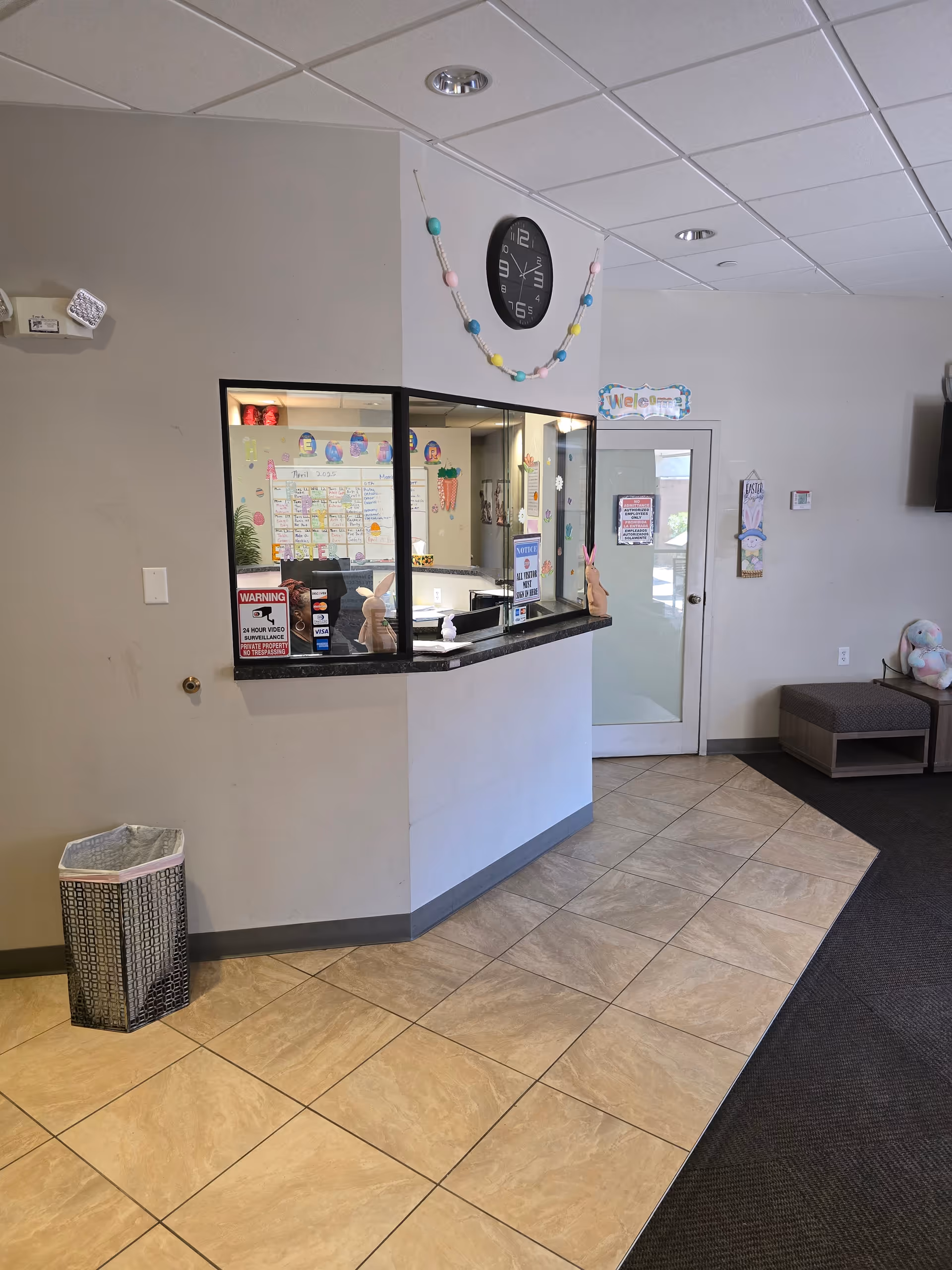 Reception desk area inside a senior living facility with bulletin boards and a clock.