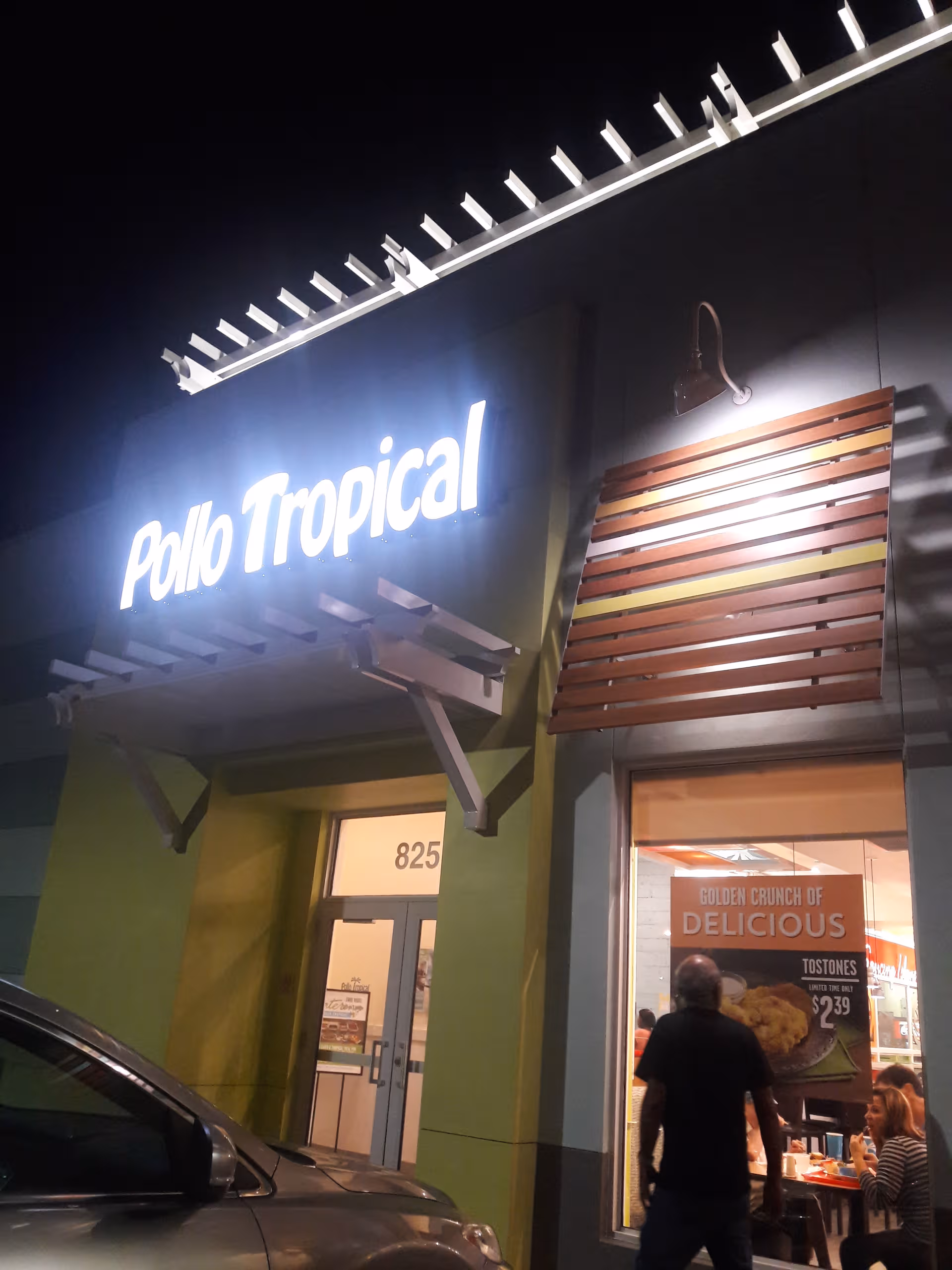 Night exterior of a Polo Tropical restaurant storefront with diners visible