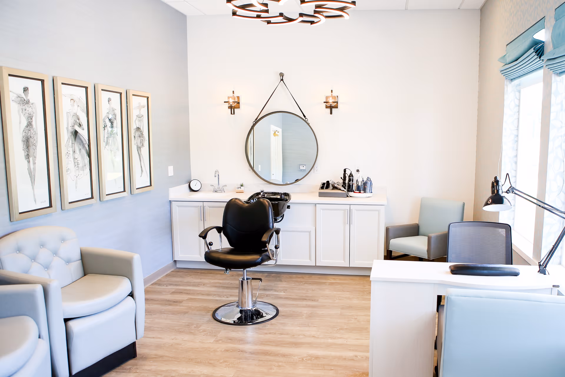 Hair salon in a senior living facility featuring a central chair, round mirror, and white cabinetry.