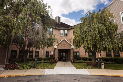Entrance to Ecorse Manor Co-op senior living building, framed by trees.