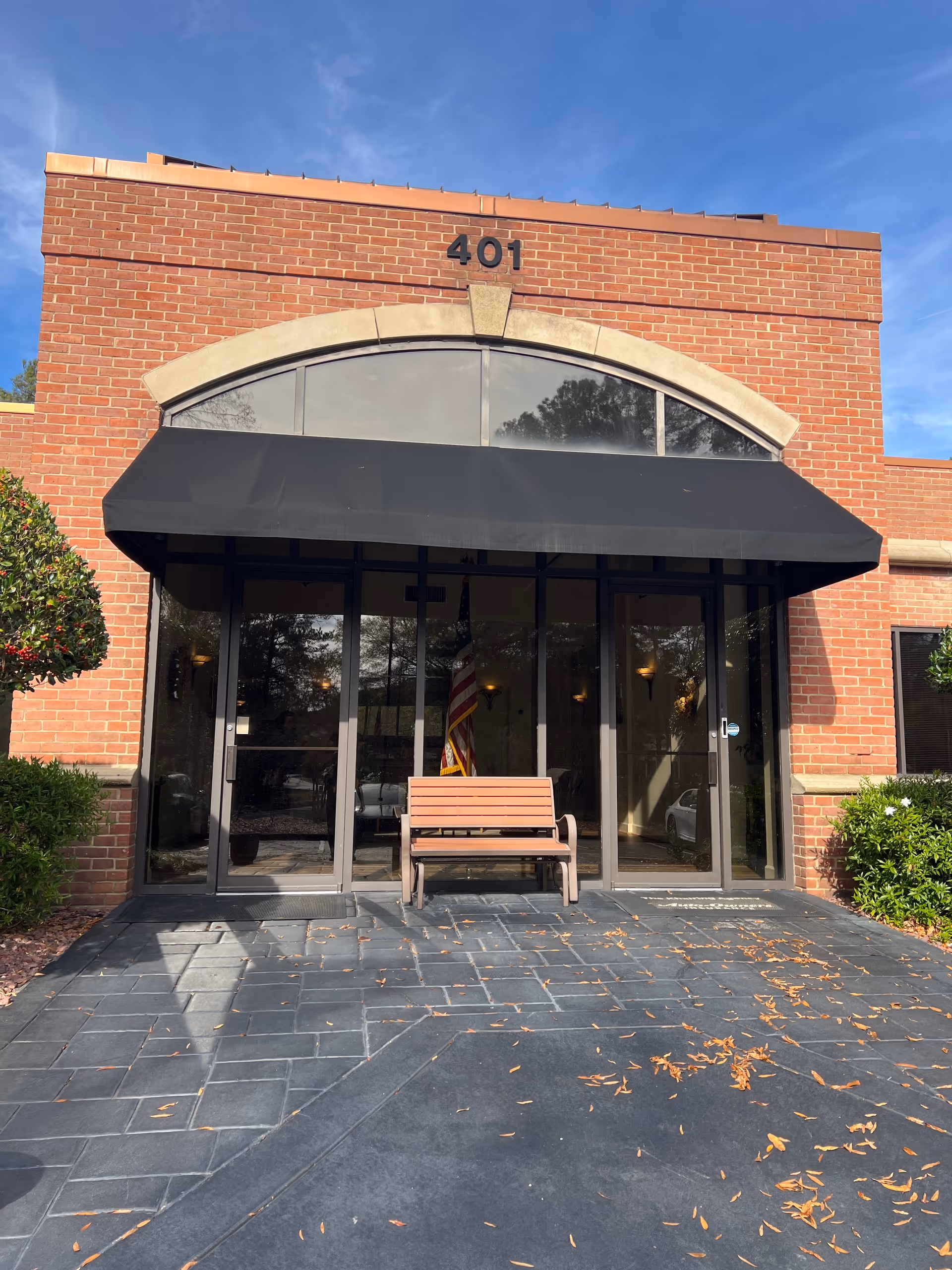 Brick building entrance with a black awning, glass doors, a bench, and 401.