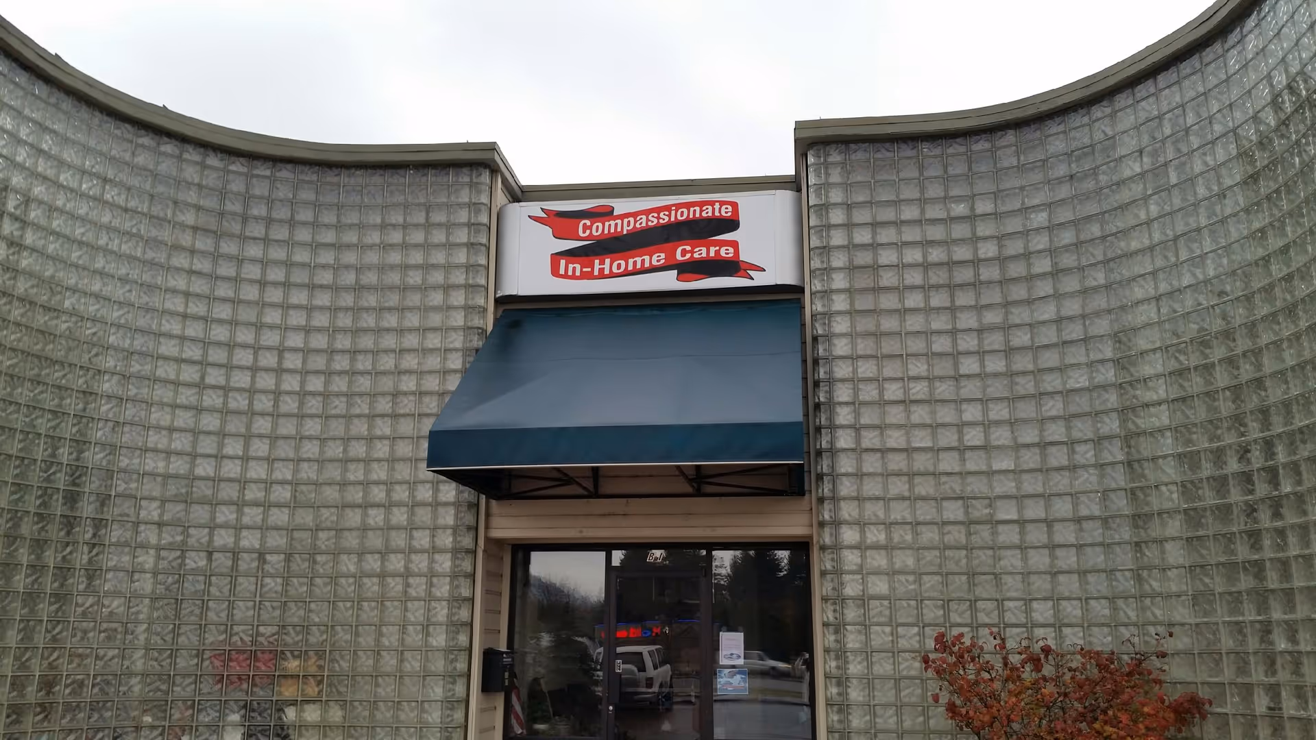 Exterior view of facility entrance with blue awning and Compassionate In-Home Care sign.