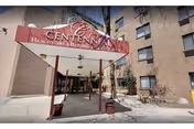 Front entrance of Centennial Healthcare and Rehabilitation Center with canopy and potted plants.