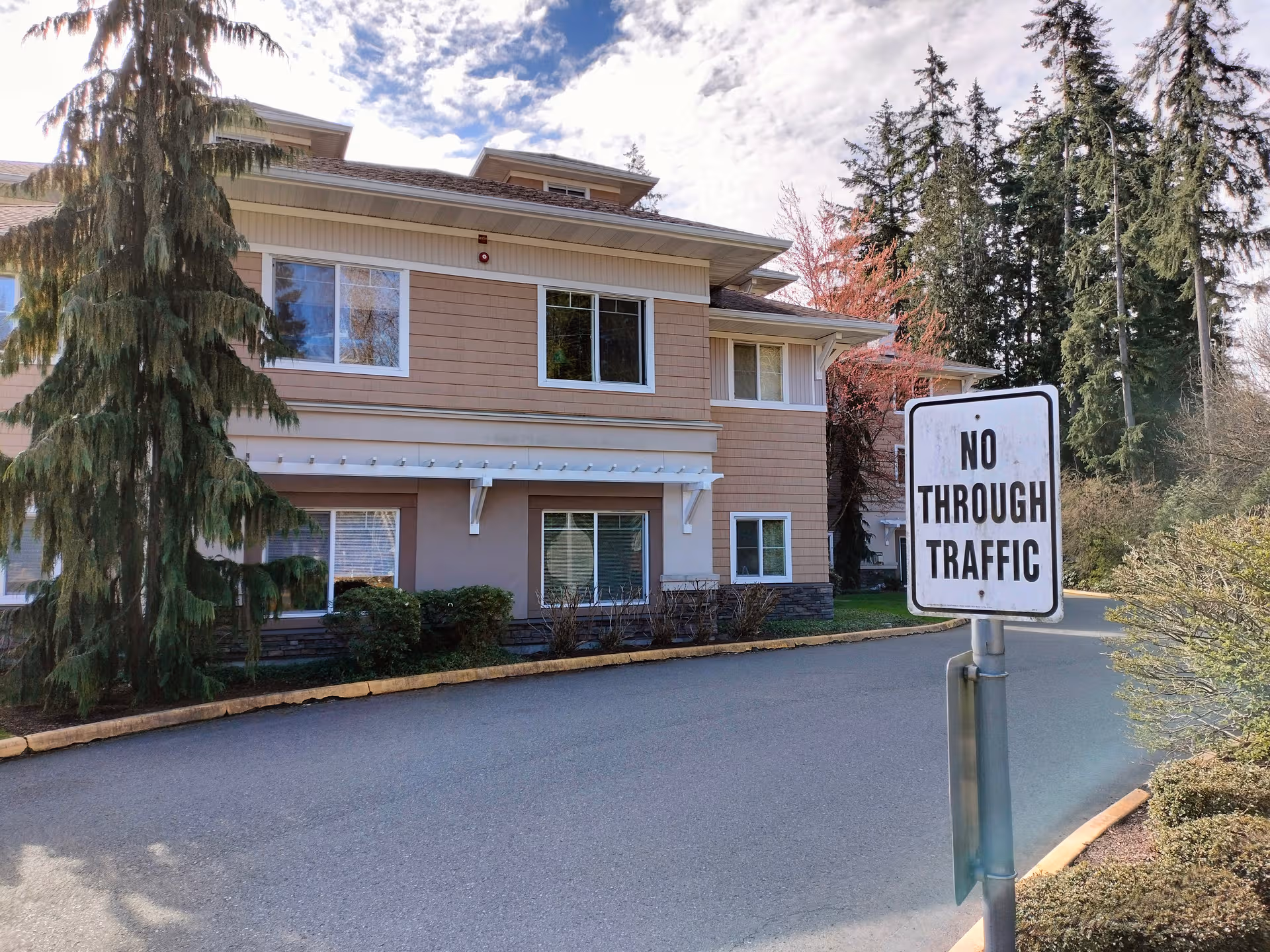 Exterior view of a multi-story senior living building with a no-through-traffic sign.
