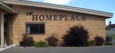Brick facility facade with HOMEPLACE sign and landscaped shrubs in front.