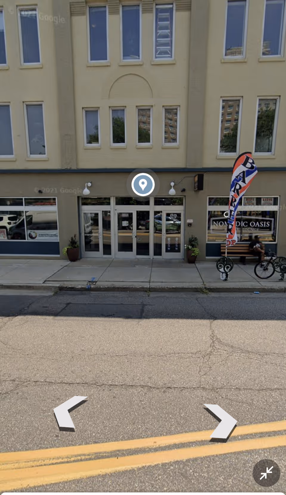 Exterior view of a beige building entrance with glass doors and storefront windows.