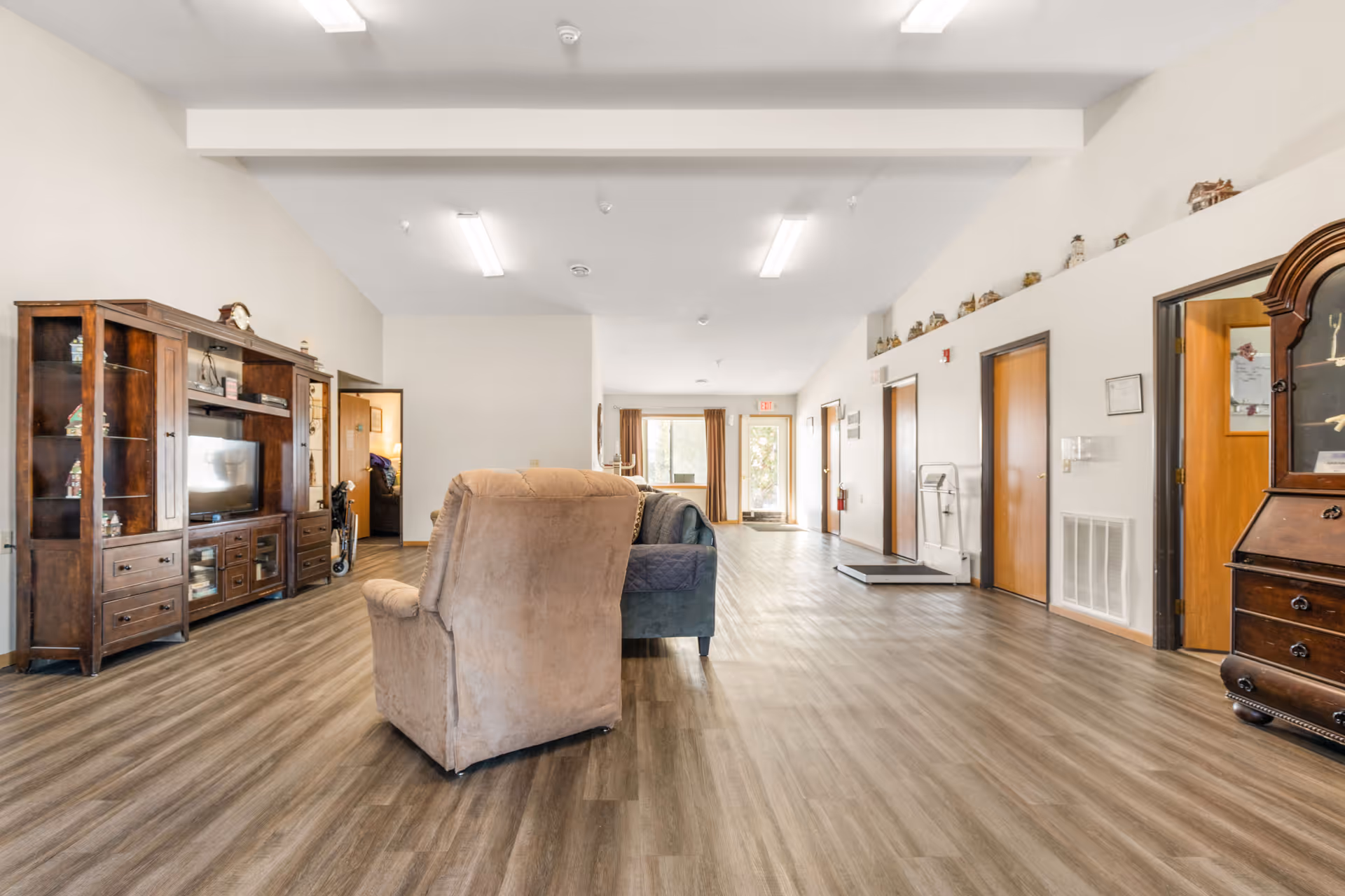 Spacious senior living lounge with couches, wood furniture, and a long corridor.