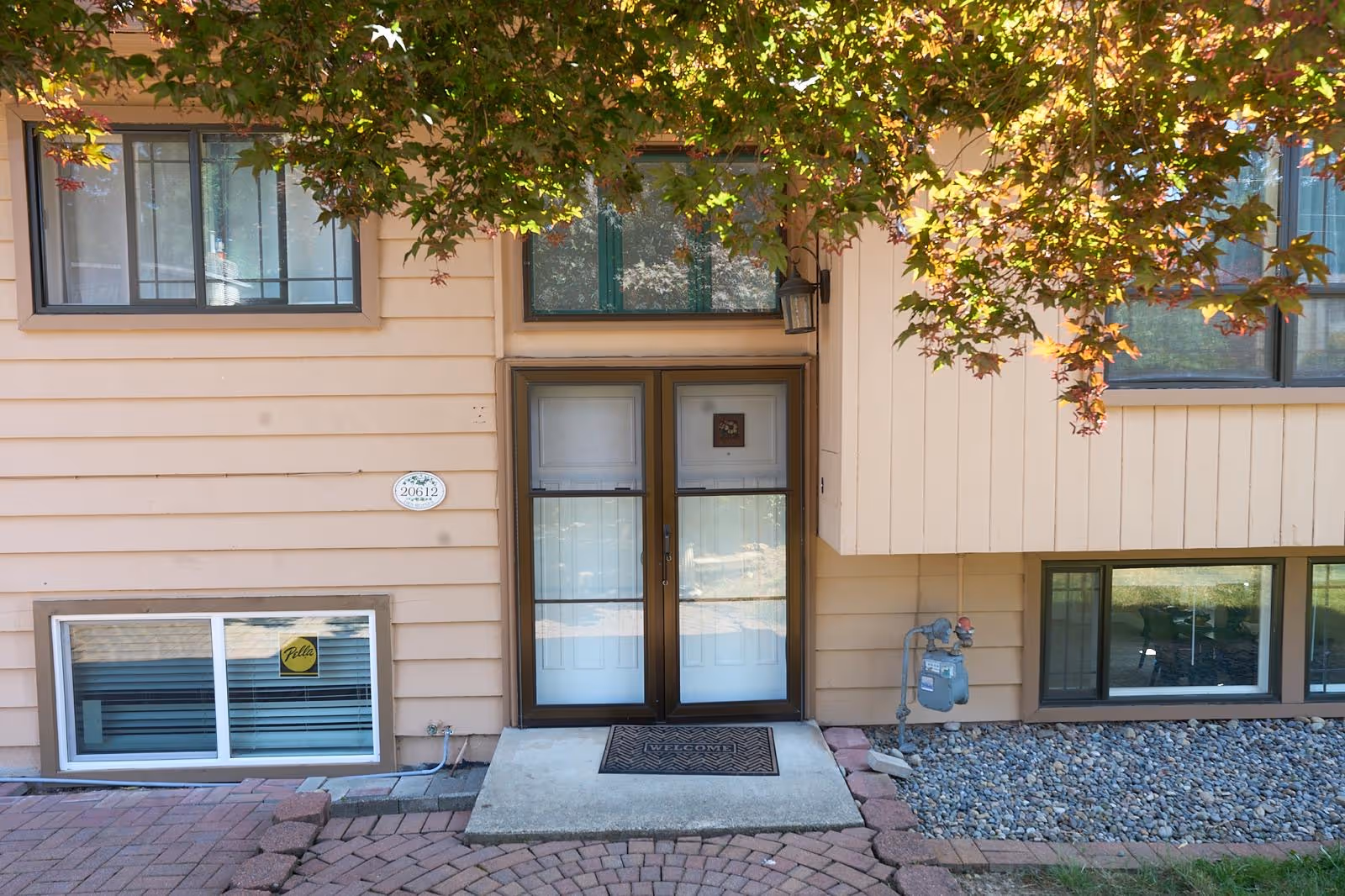 Beige two-story building exterior with glass doors, windows, and a welcome mat at entrance.