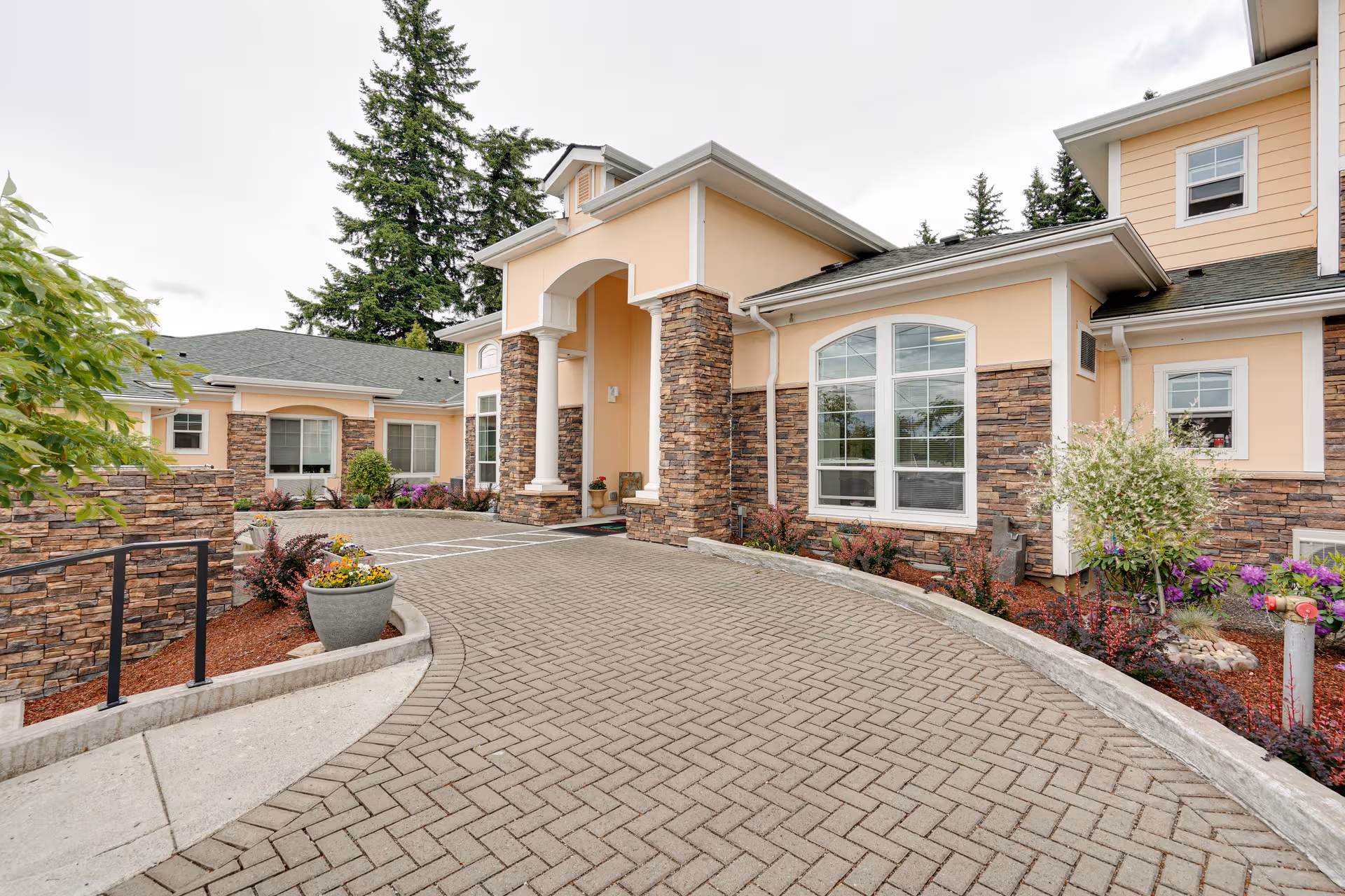 Front exterior view of a tan senior living facility with stone accents and landscaped entrance.